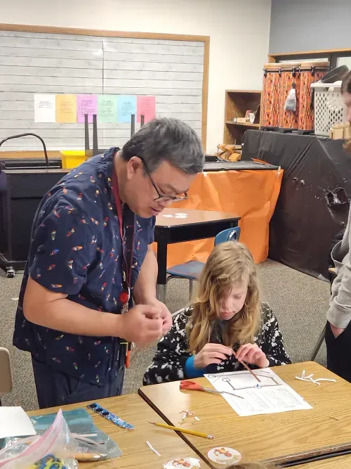 student reading instructions and adult helping them complete their project