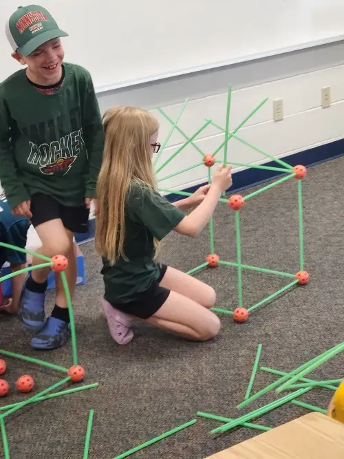 students using sticks and connectors to build a house