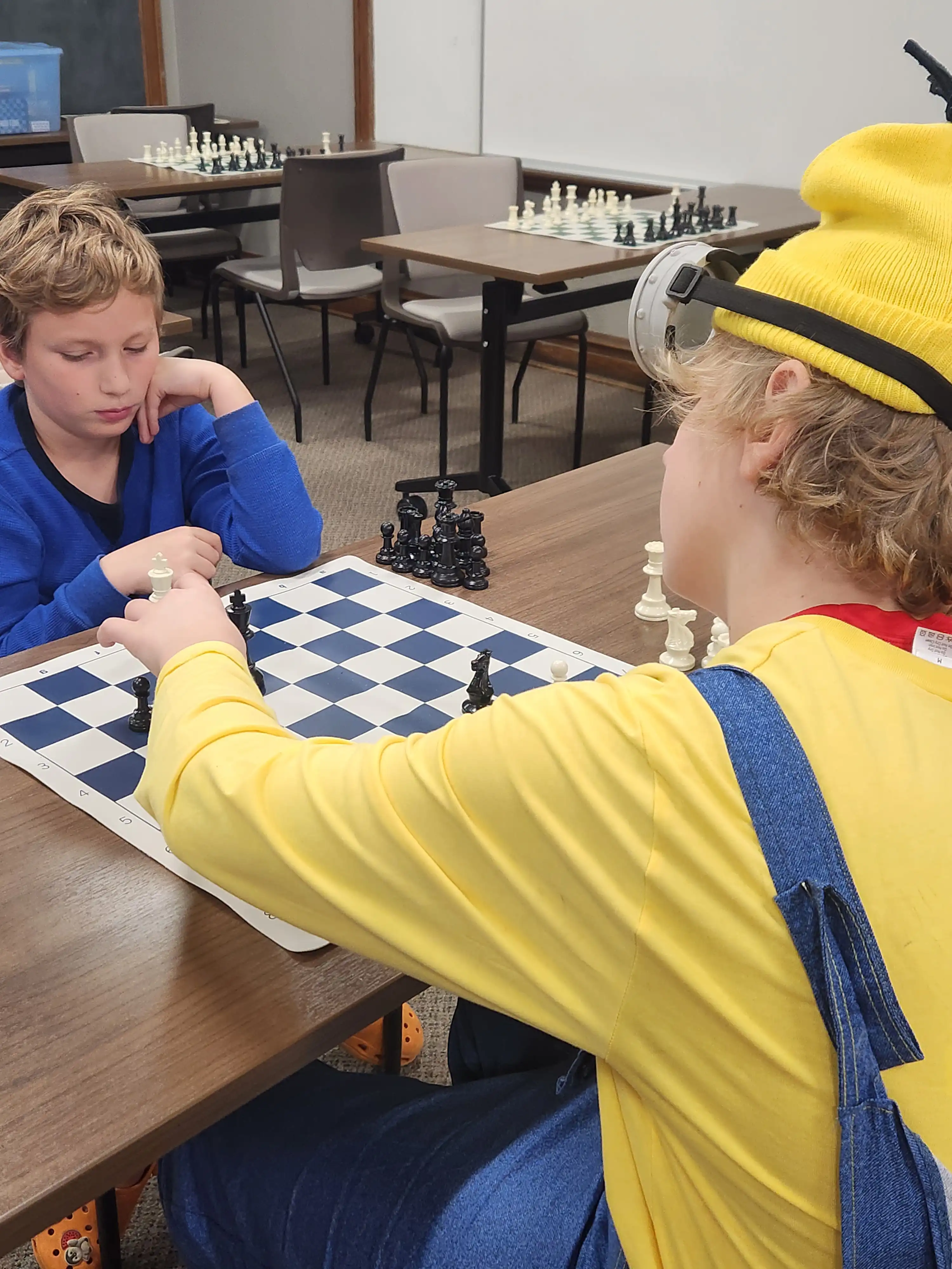 2 students playing chess with one wearing a costume