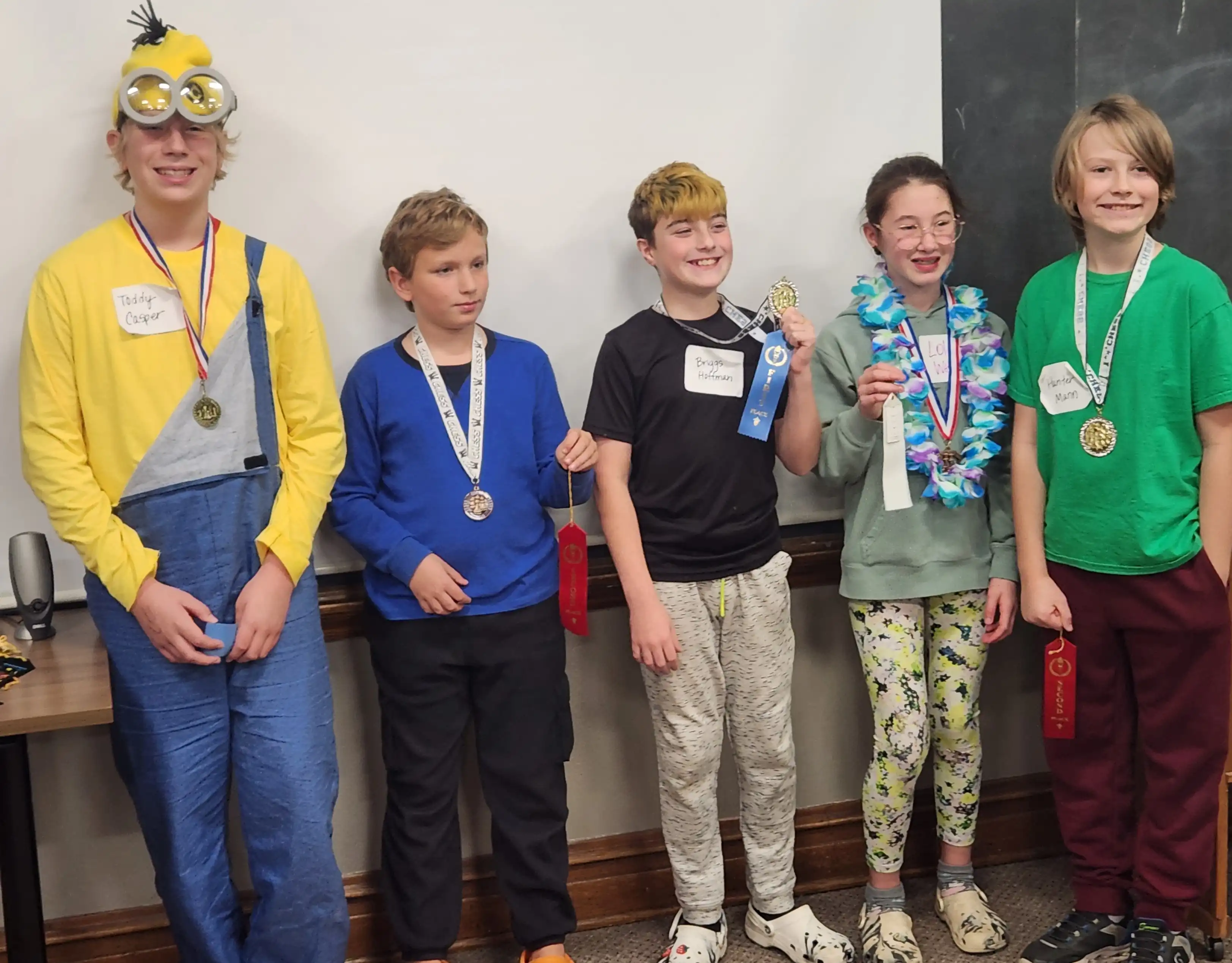 5 students standing with their chess ribbons on their neck.