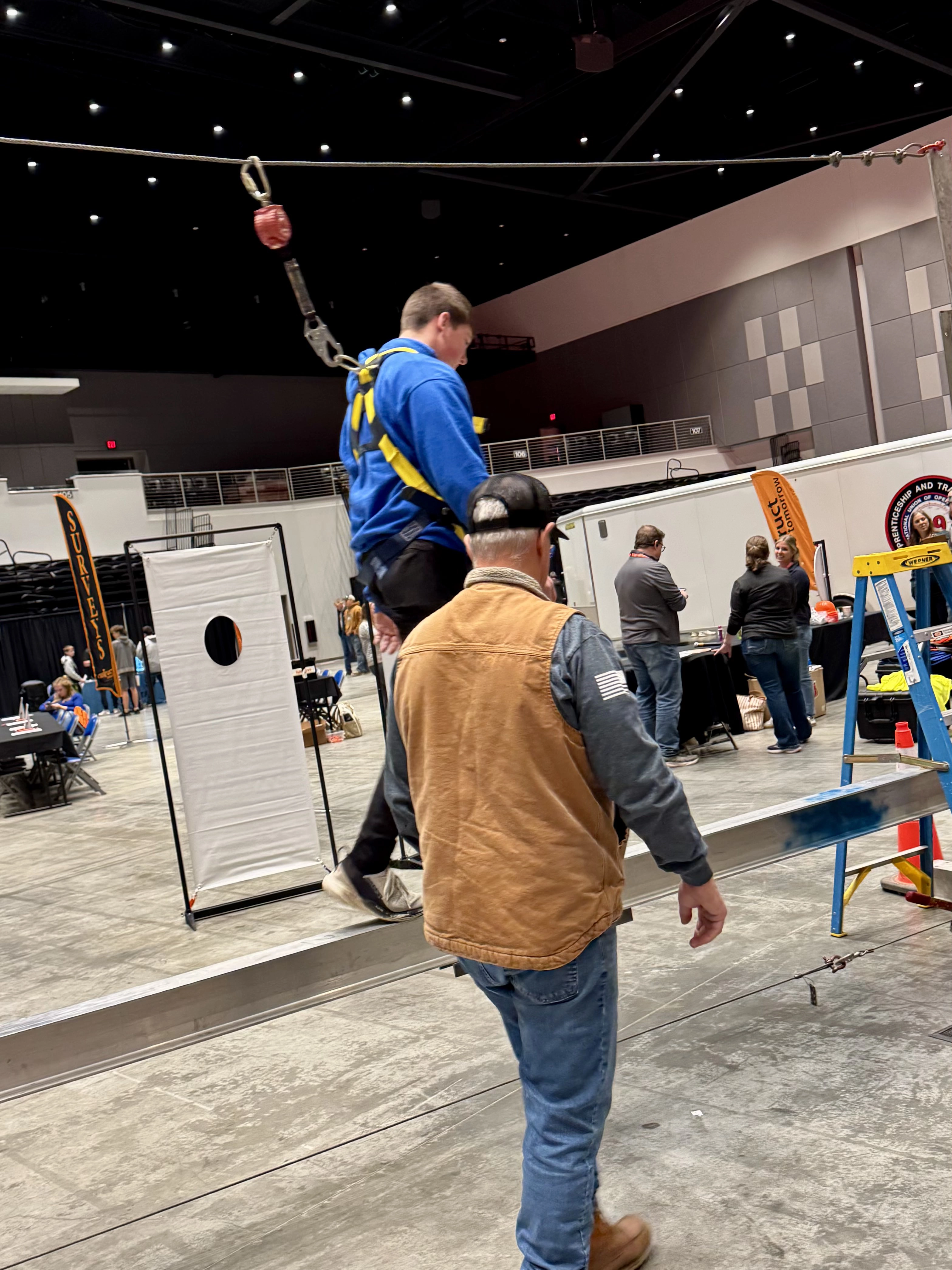 Student walking on beam in a harness
