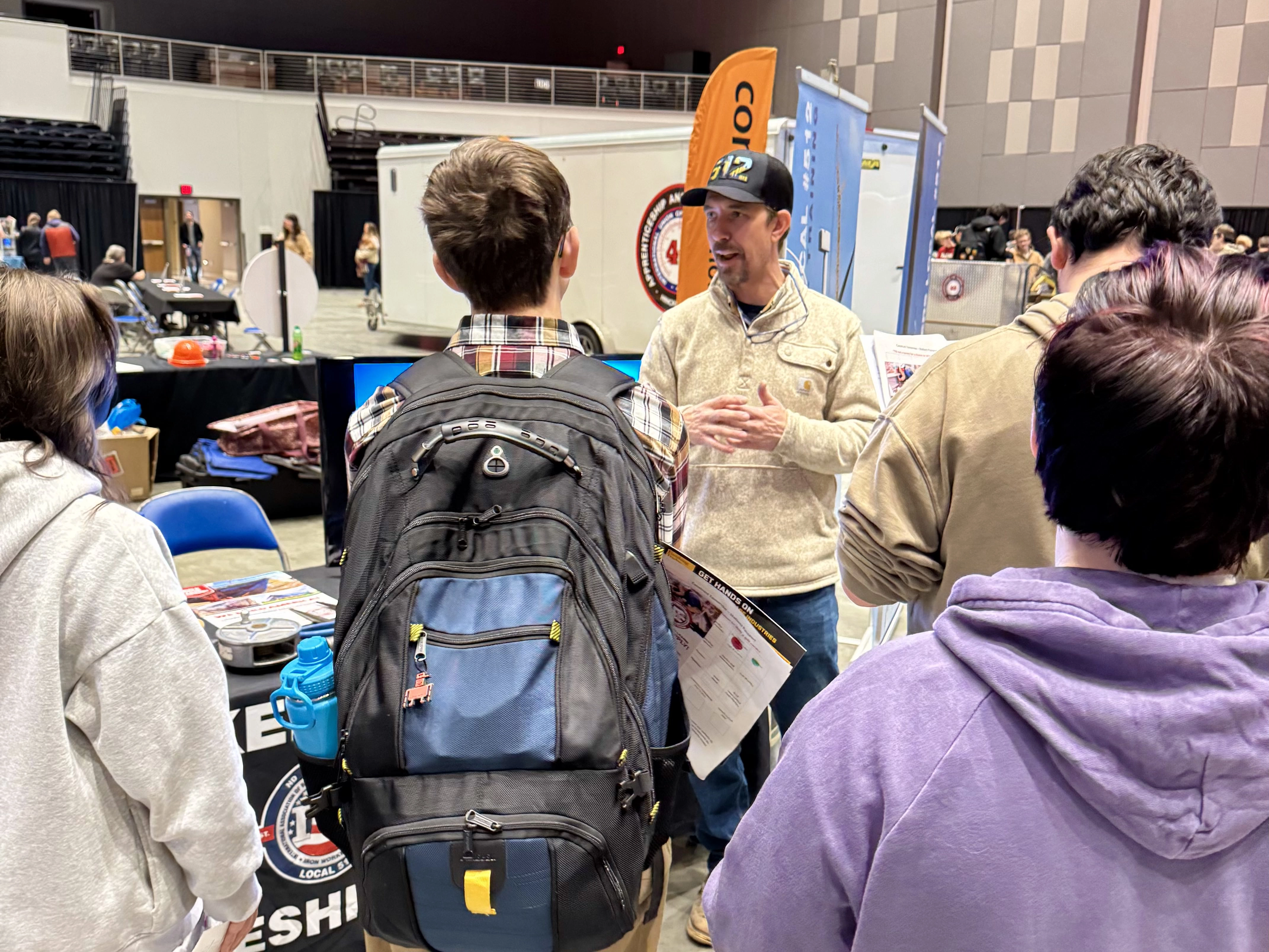 Students standing around a booth learning about a trade