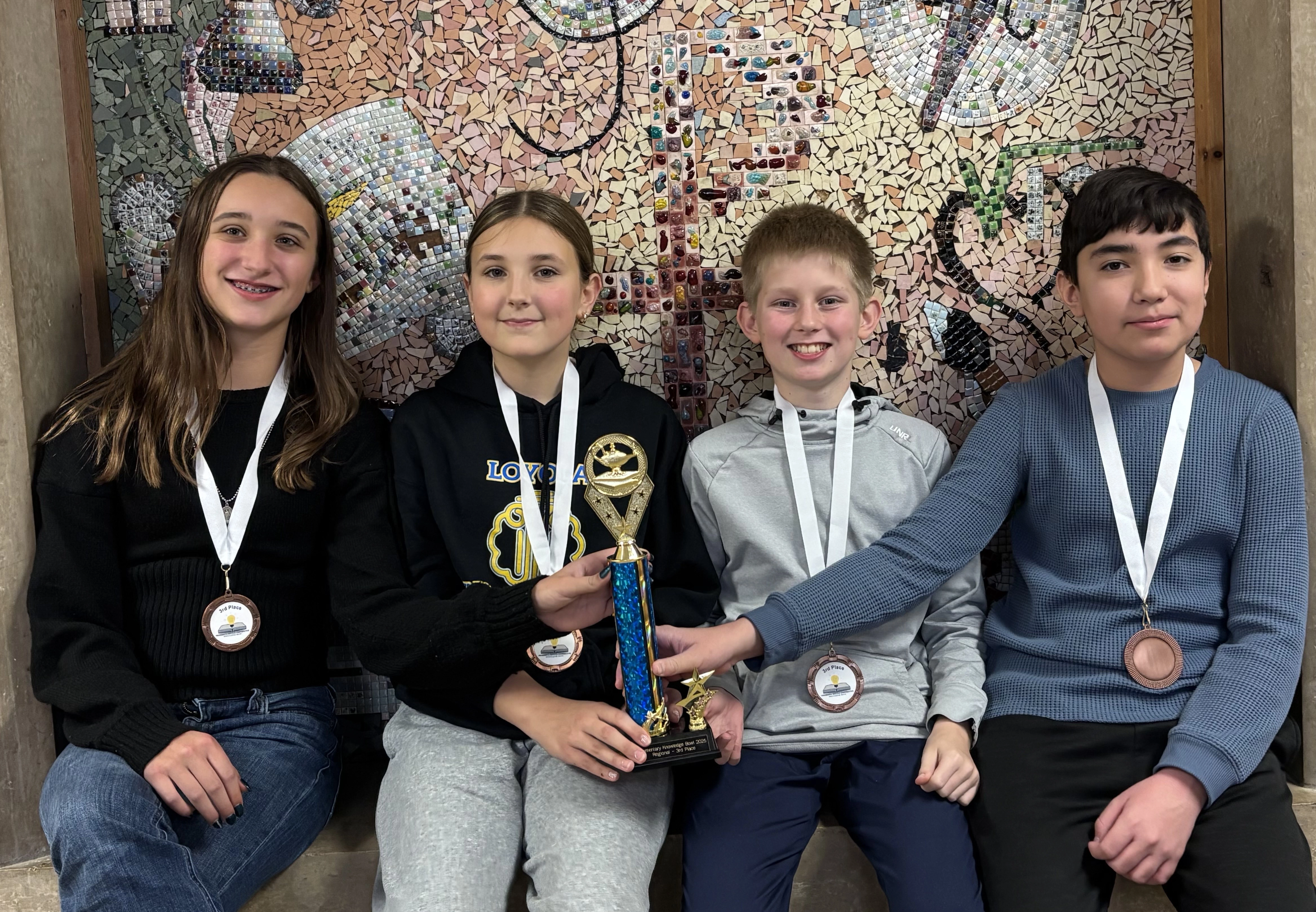 Students wearing medals and posing with a trophy