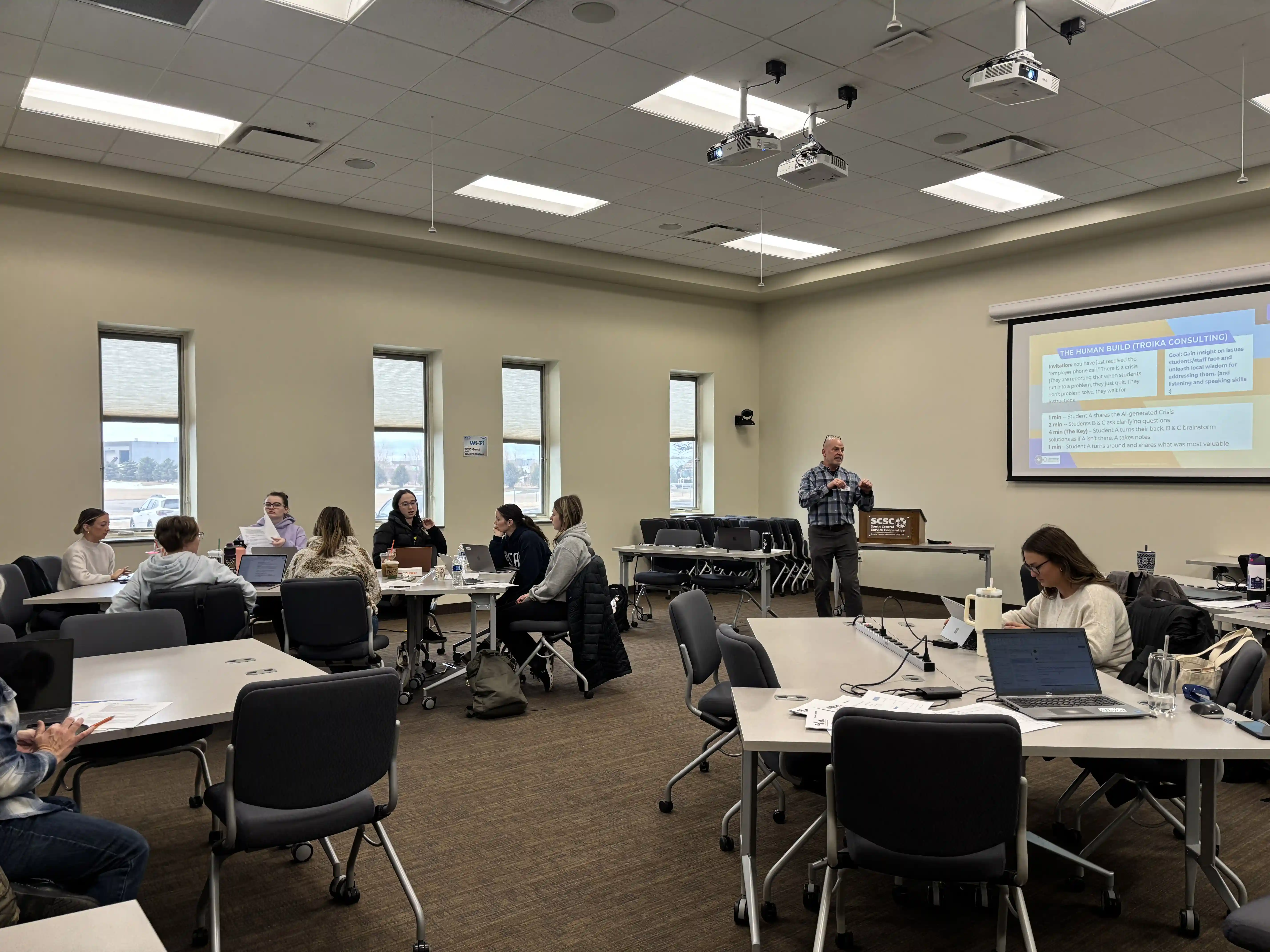 view of educators sitting at tables around the room listening to the speaker at the front