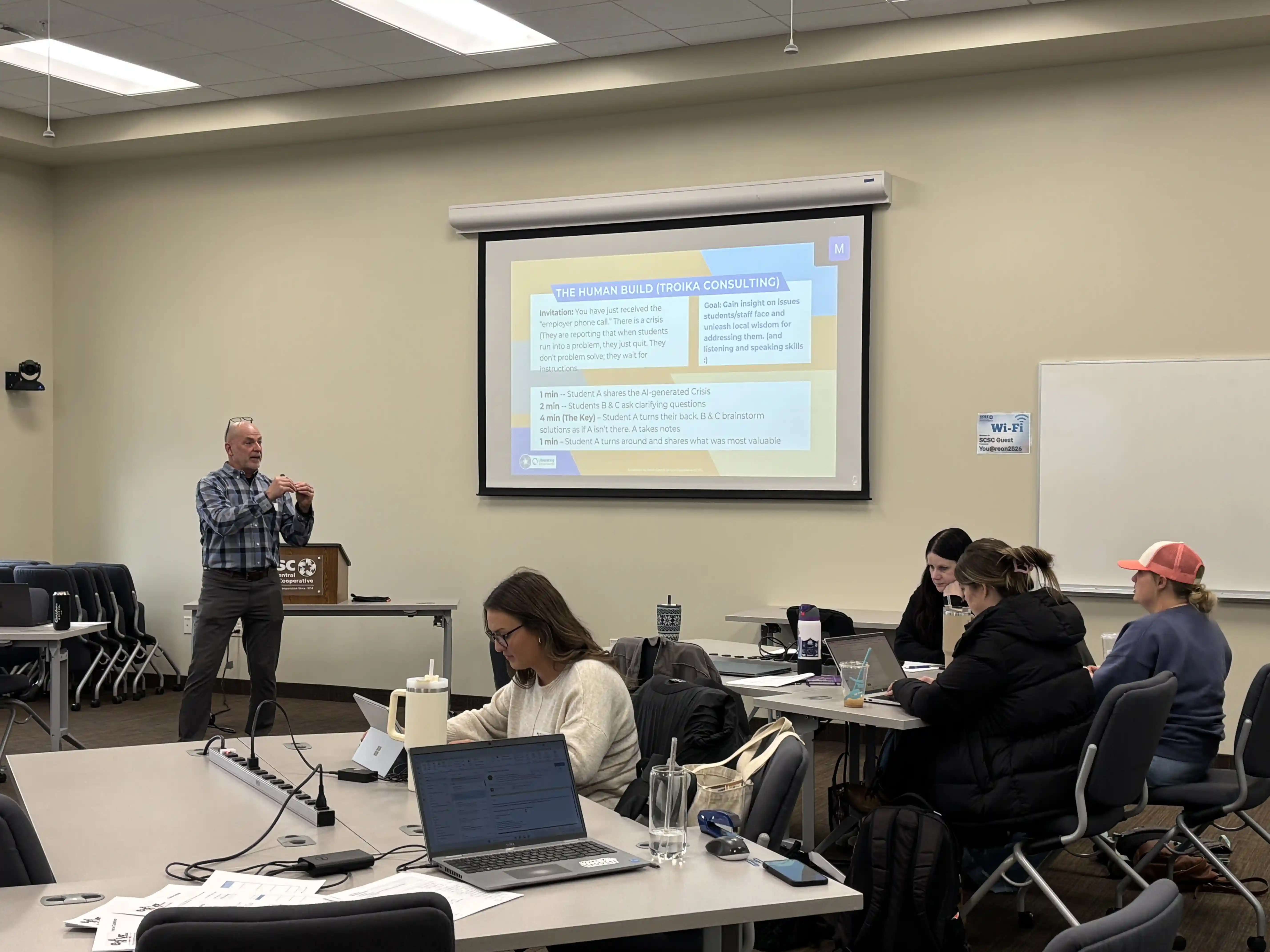 Close up view of 2 tables of educators listening to the presenter