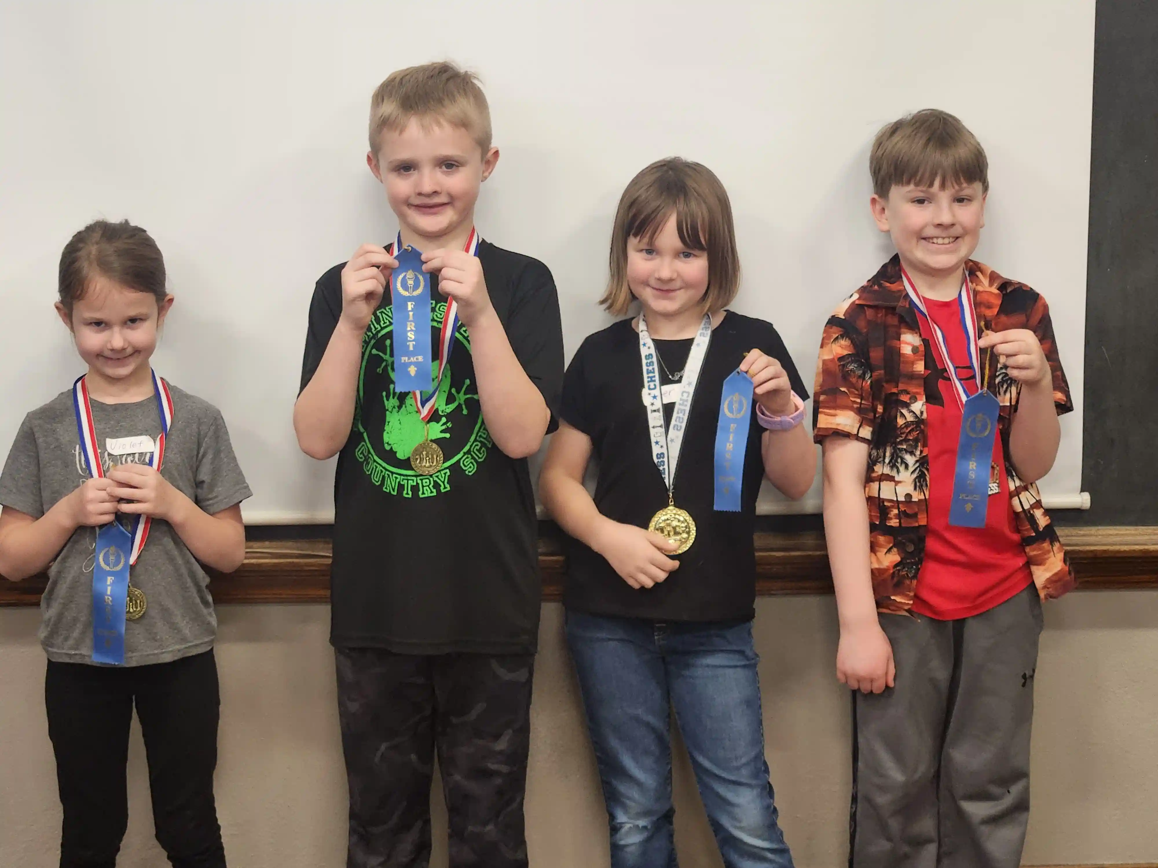 4 students smiling at the camera holding their ribbons up.