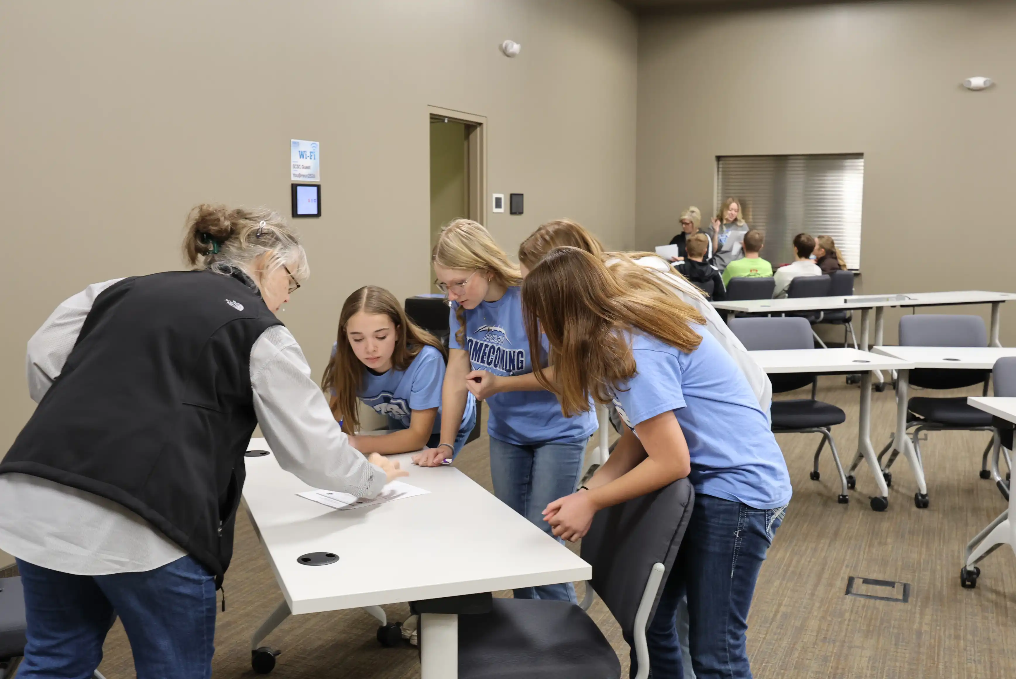 teacher on one side of the table and 3 students on the other side