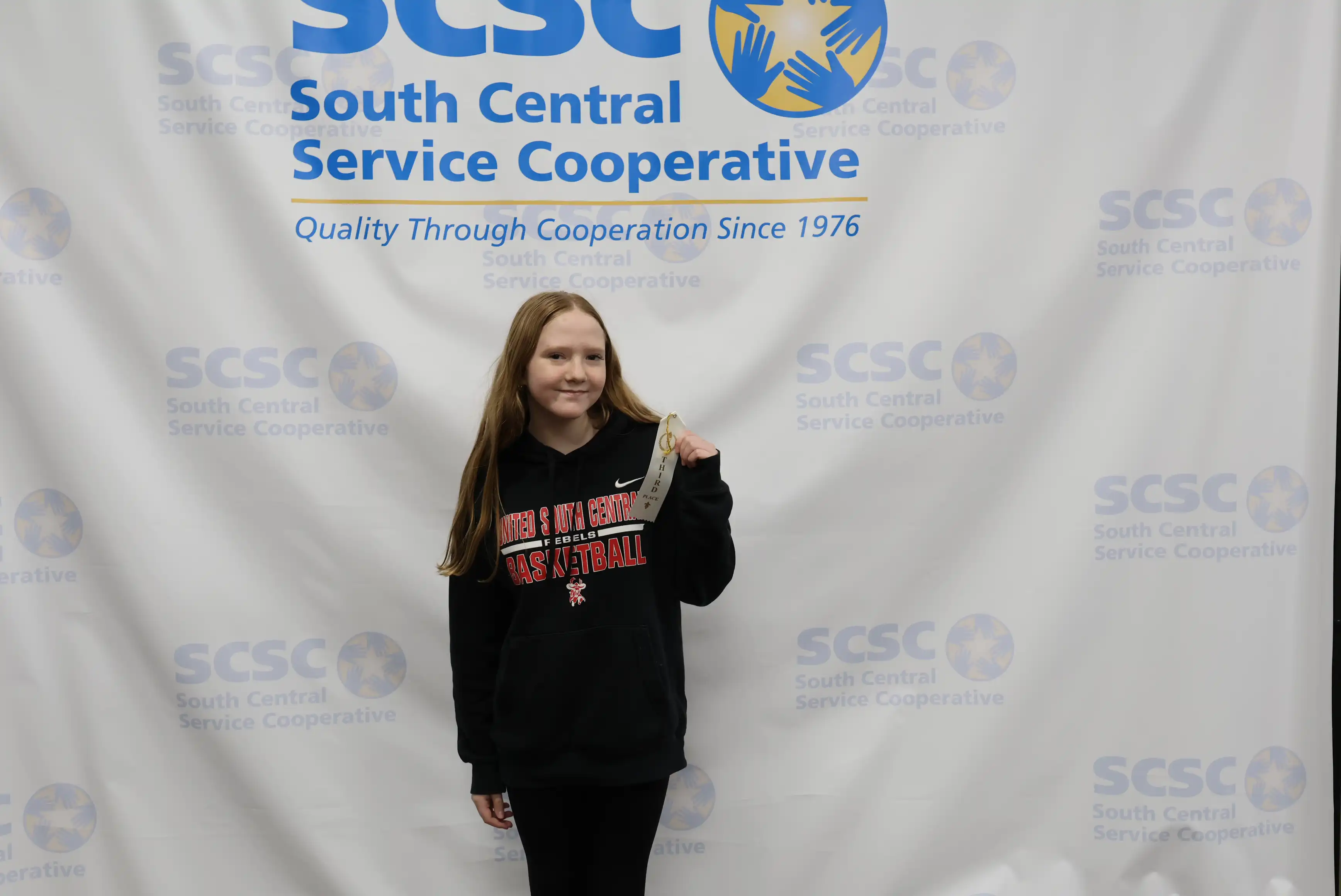 student holding up ribbon and wearing a medal