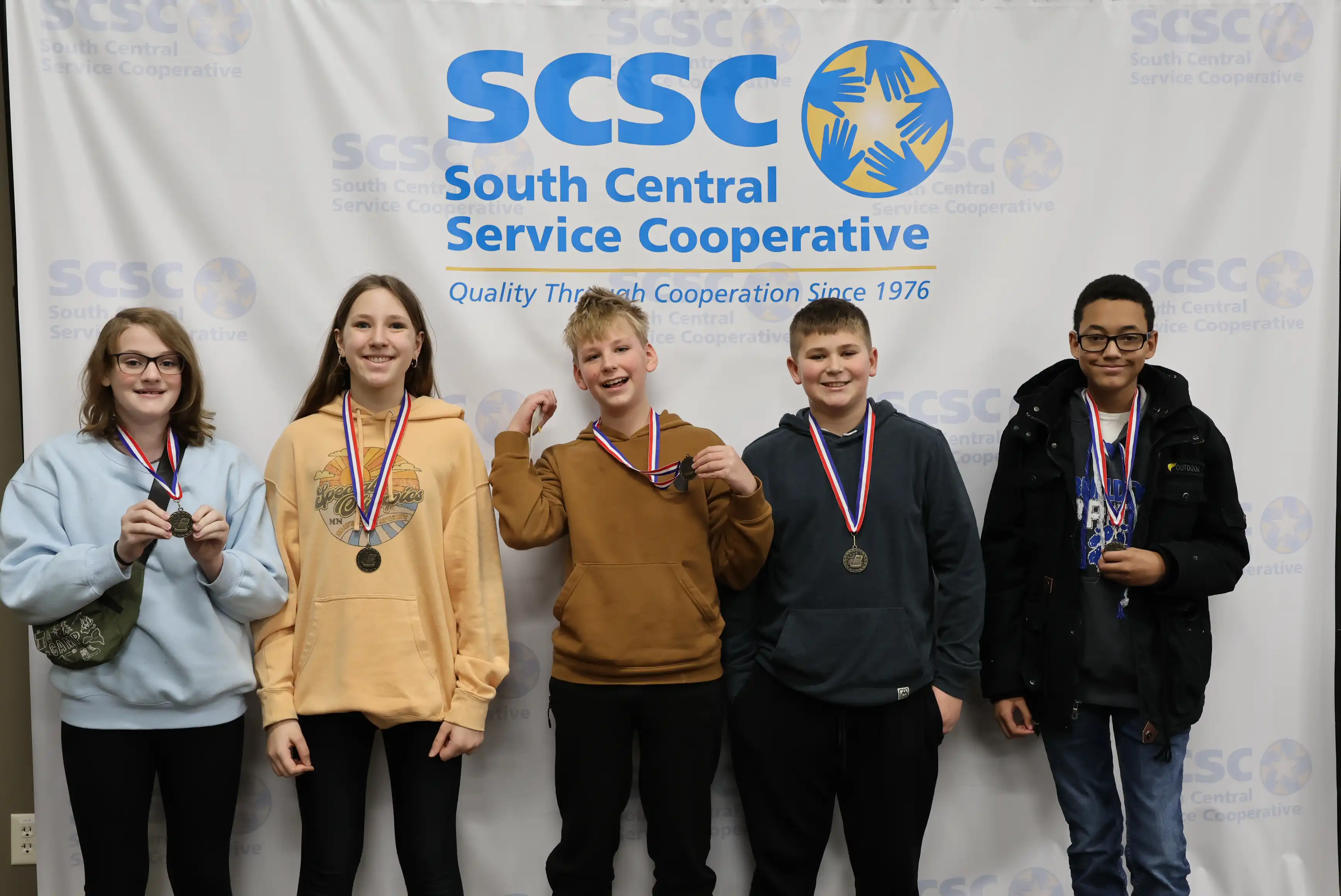 5 students smiling wearing their medals