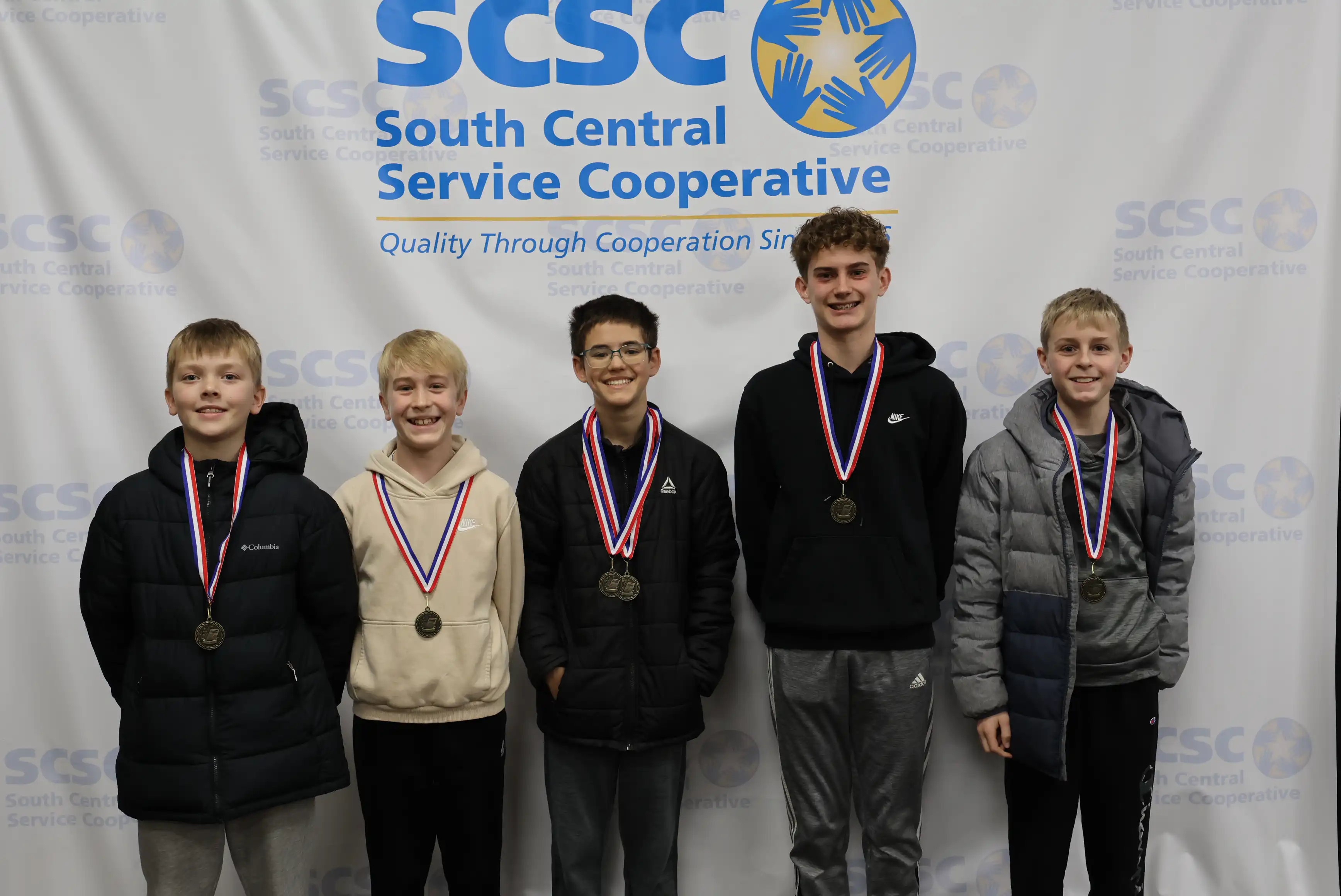 5 students smiling wearing their medals
