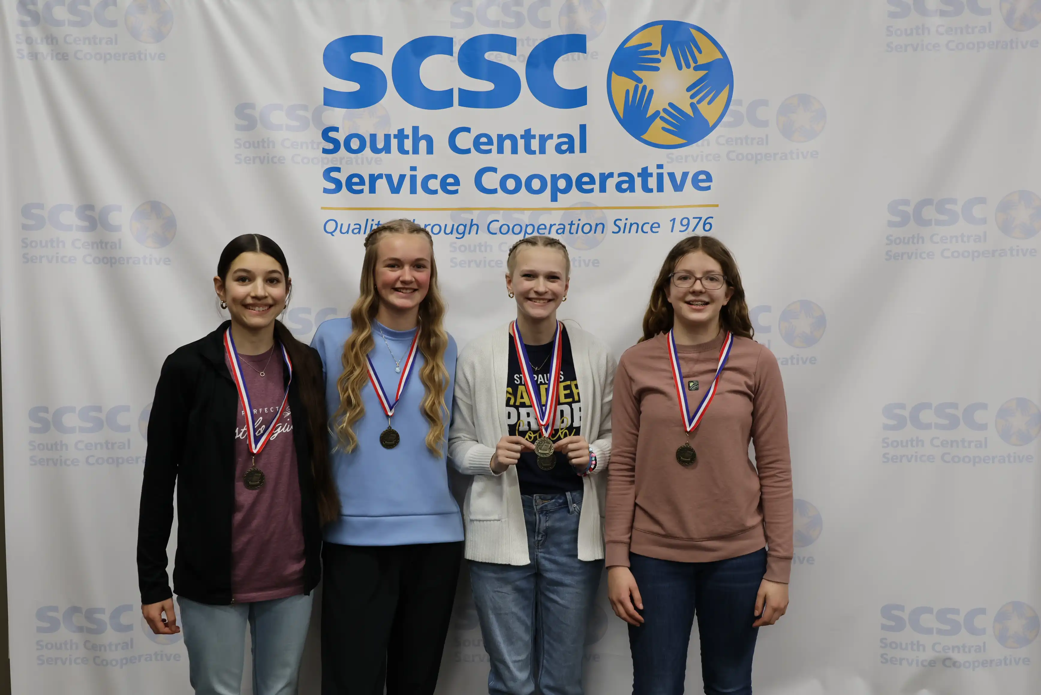 4 students smiling wearing their medals