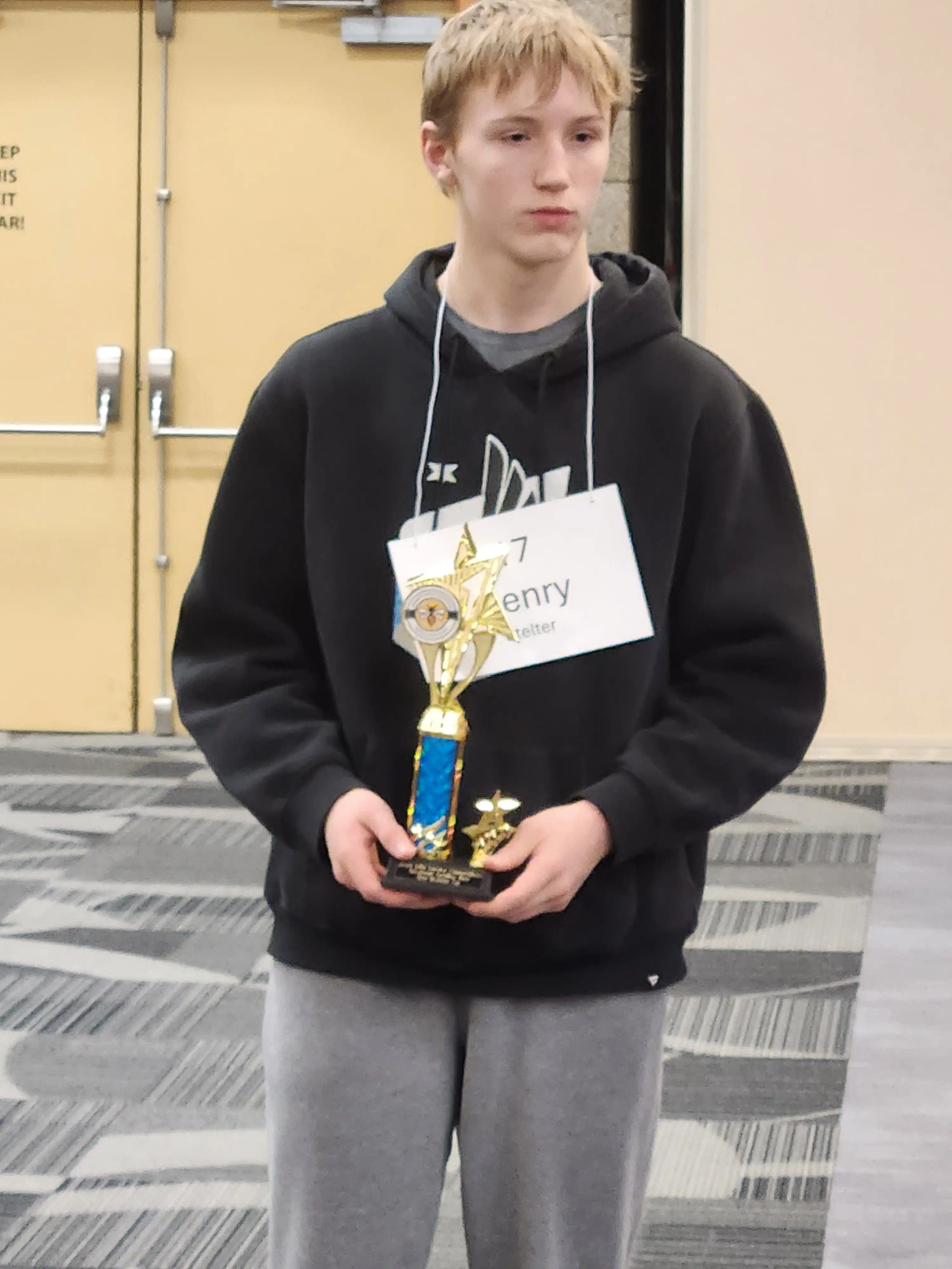 student smiling and holding trophy