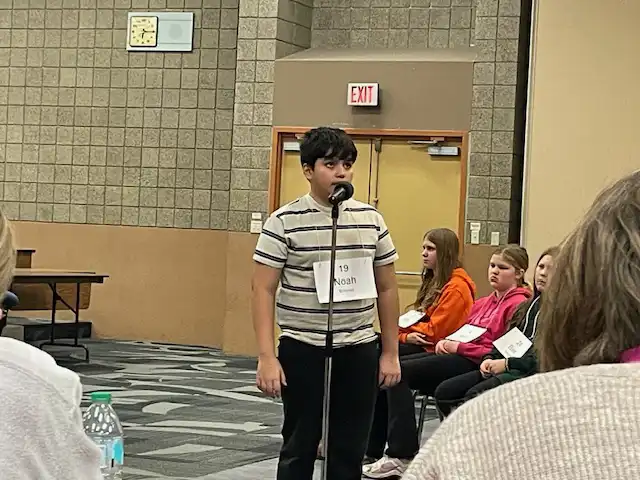 student standing by microphone spelling a word