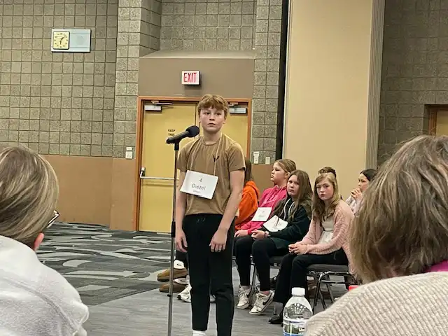 student standing by microphone spelling a word