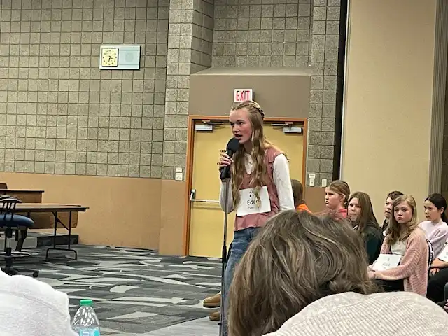 student standing by microphone spelling a word