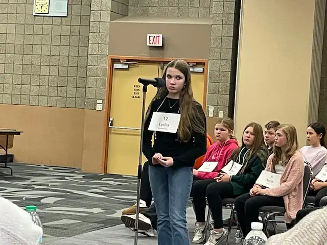 student standing by microphone spelling a word