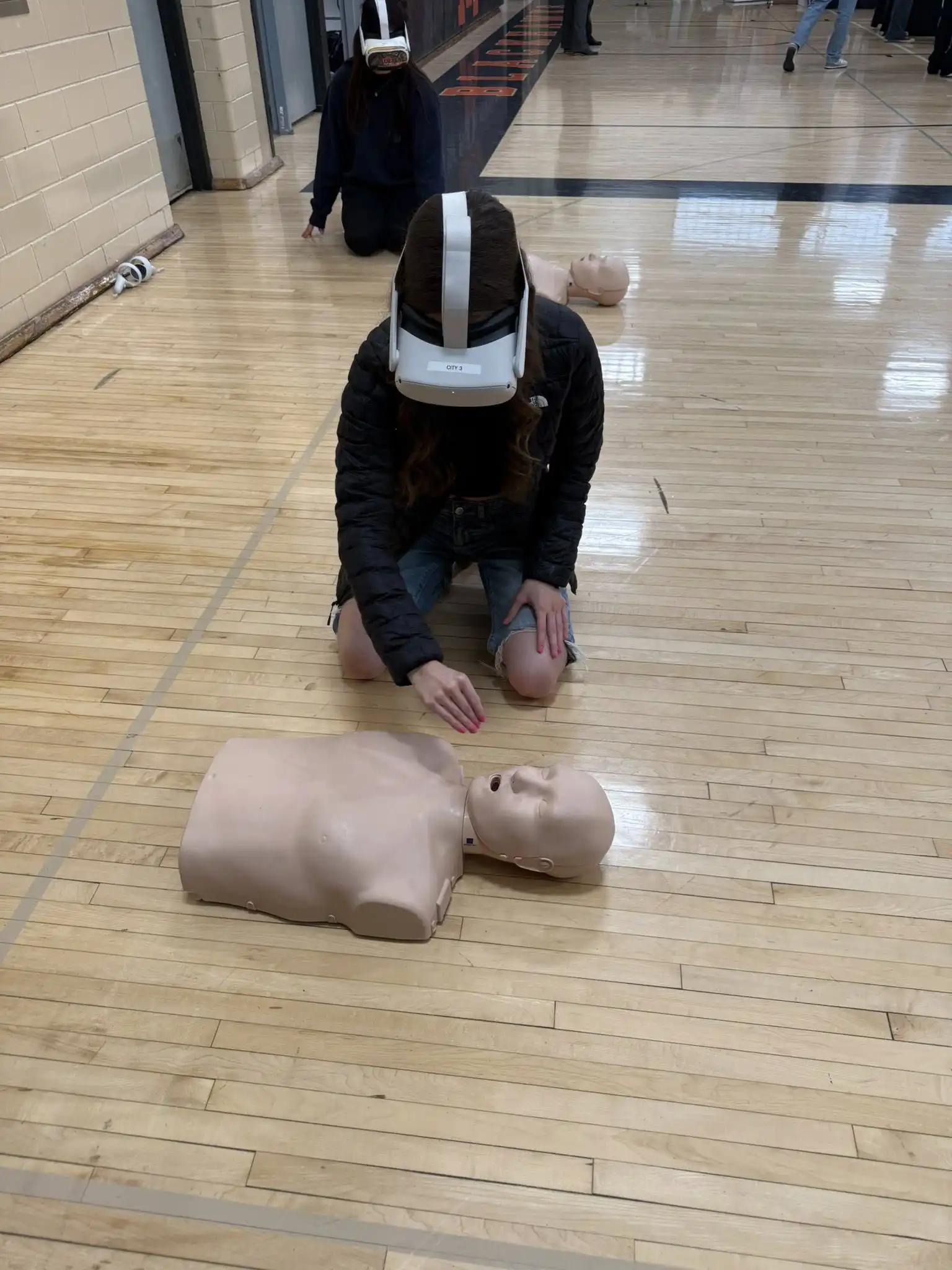 student wearing VR set and practicing CPR on a dummy