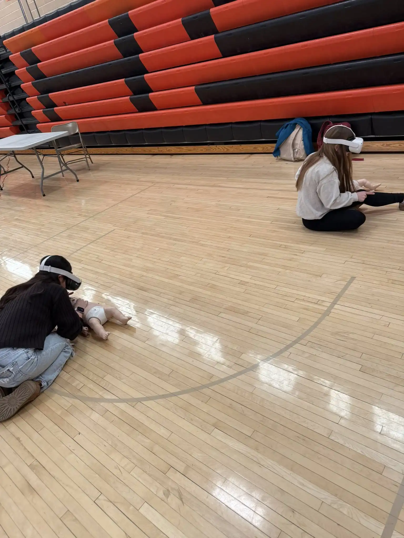 student wearing VR set and practicing CPR on a baby dummy