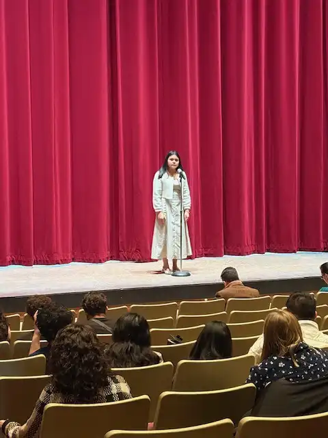 student standing on stage and reciting their poem