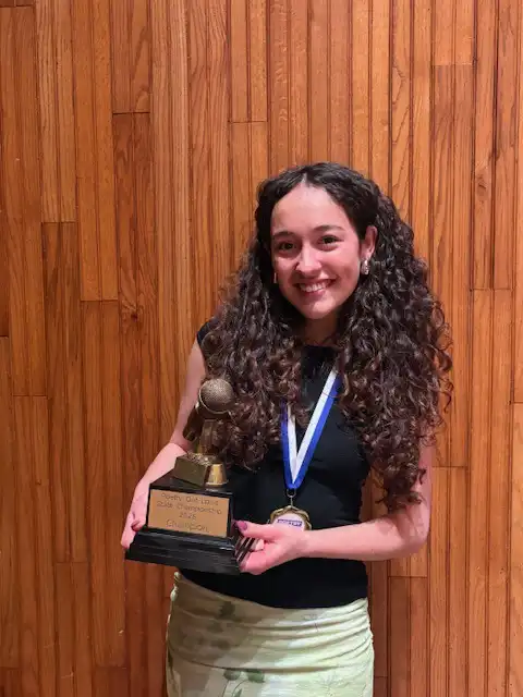 Student smiling and holding their award that is a mirophone