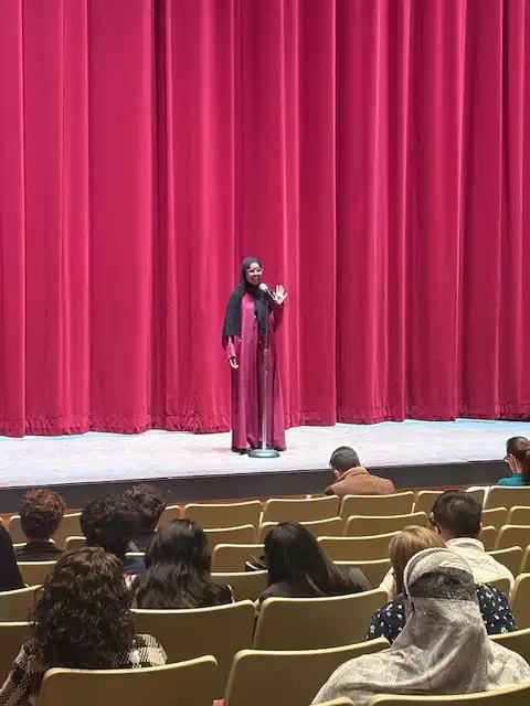 student standing on stage and reciting their poem