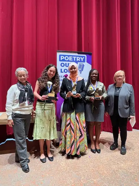 group of students and adults on stage with medals and awards