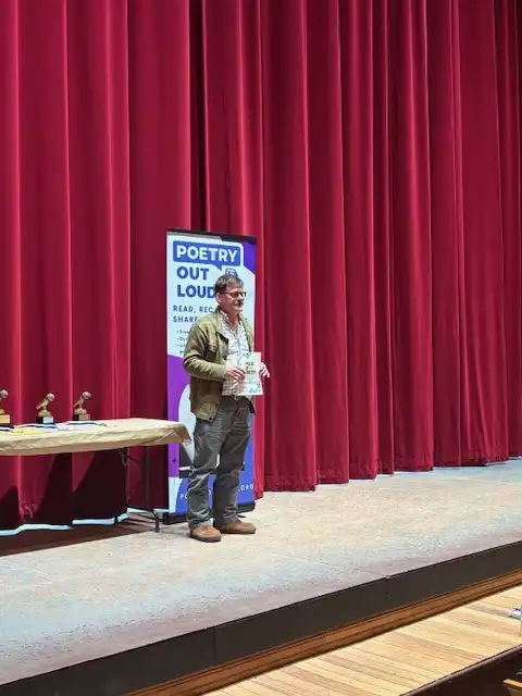 Student standing on stage with their award