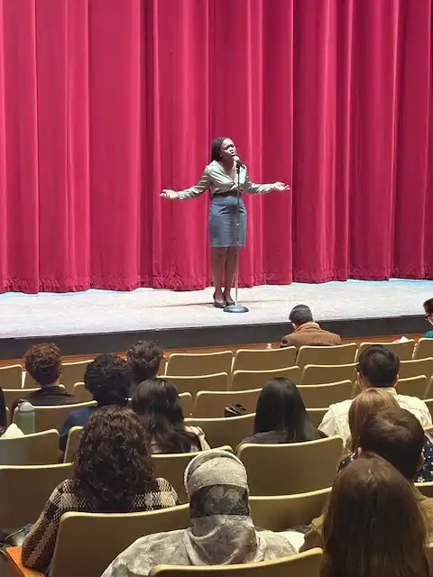 student standing on stage and reciting their poem