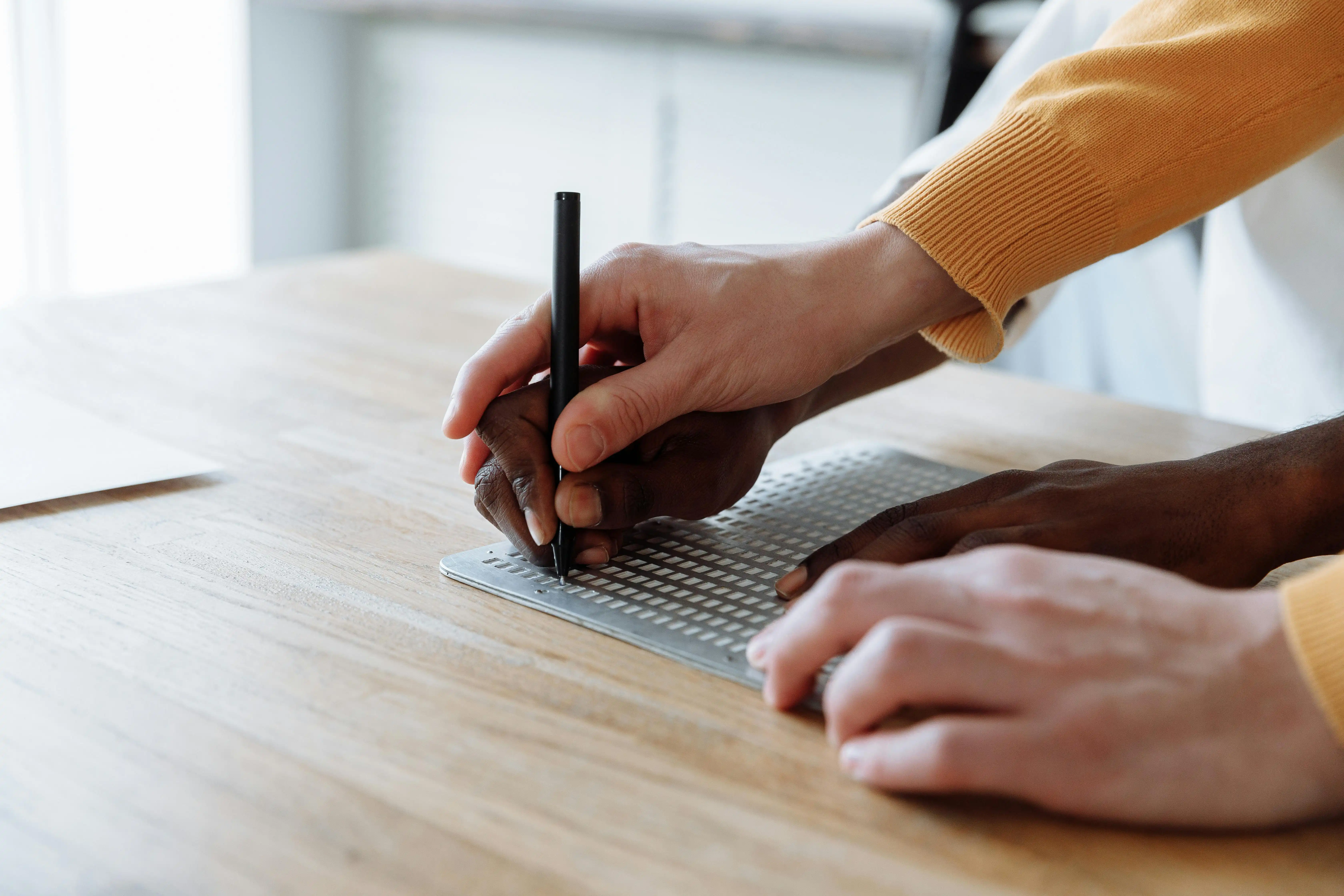teacher helping student use device for writing with braille