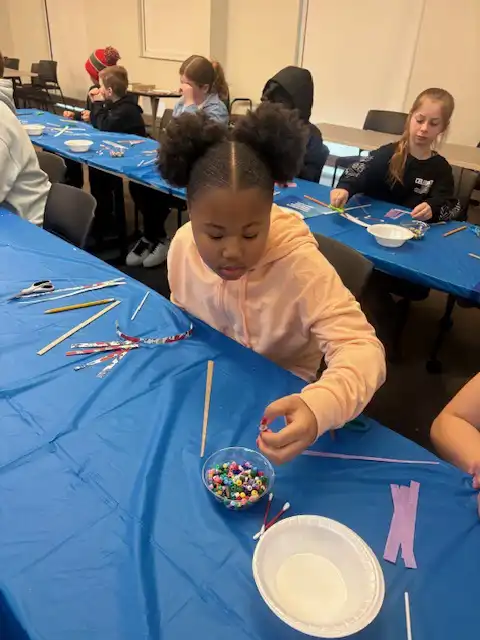 student working on a project with a group of beads sitting in front of her.