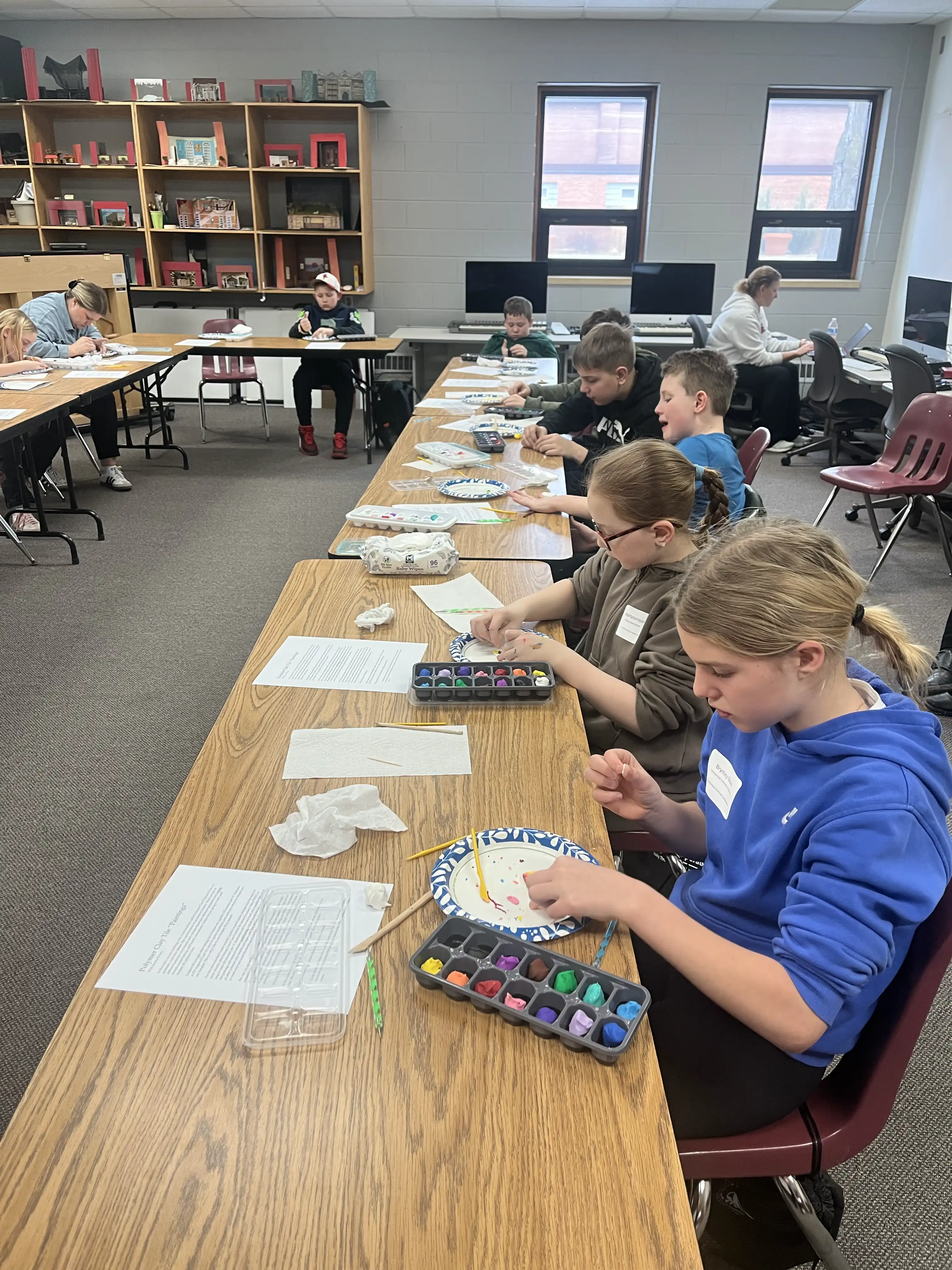 a table of students looking down and working on their clay projects