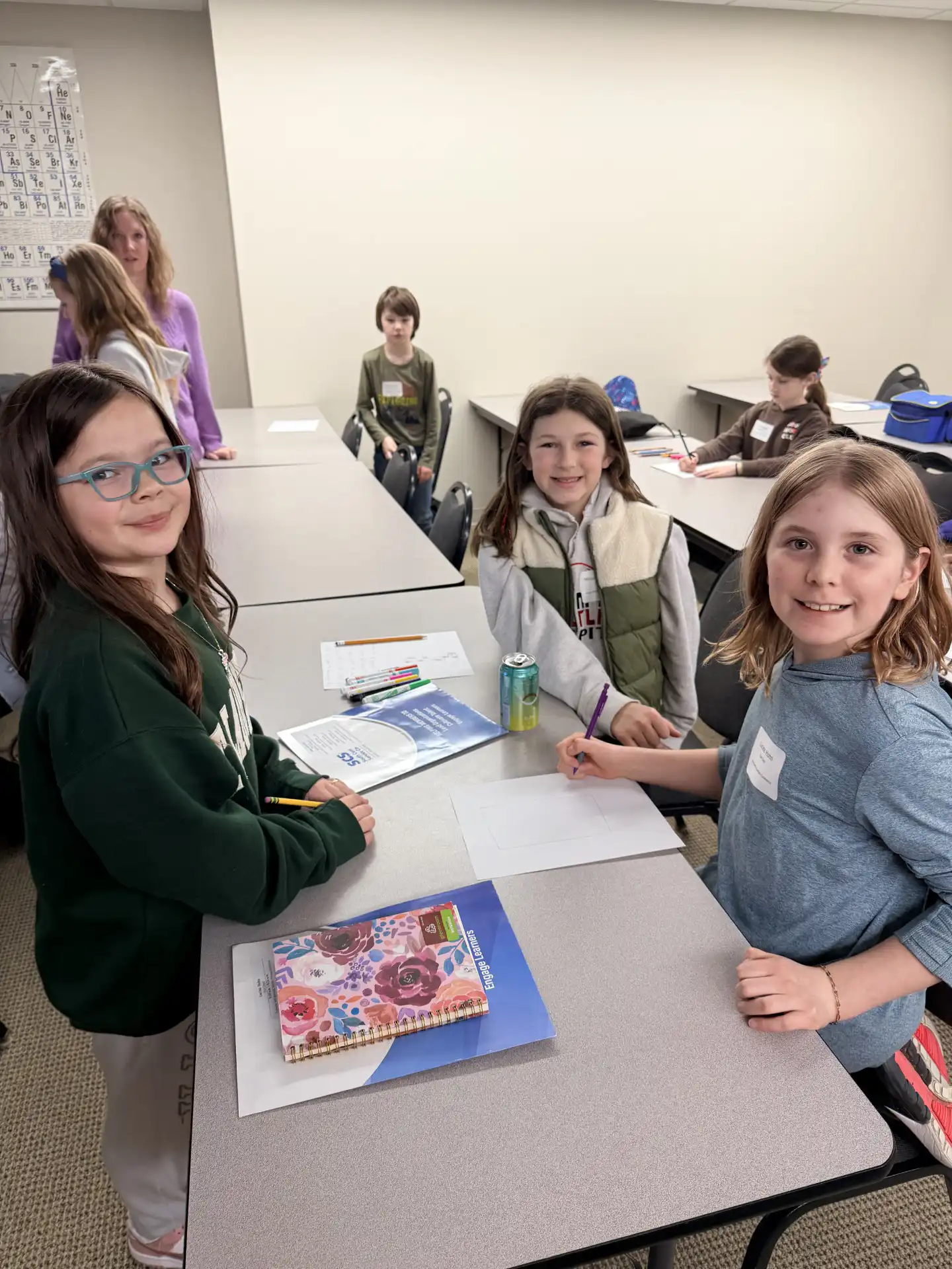 students looking up from the paintings they are working on and smiling at the camera