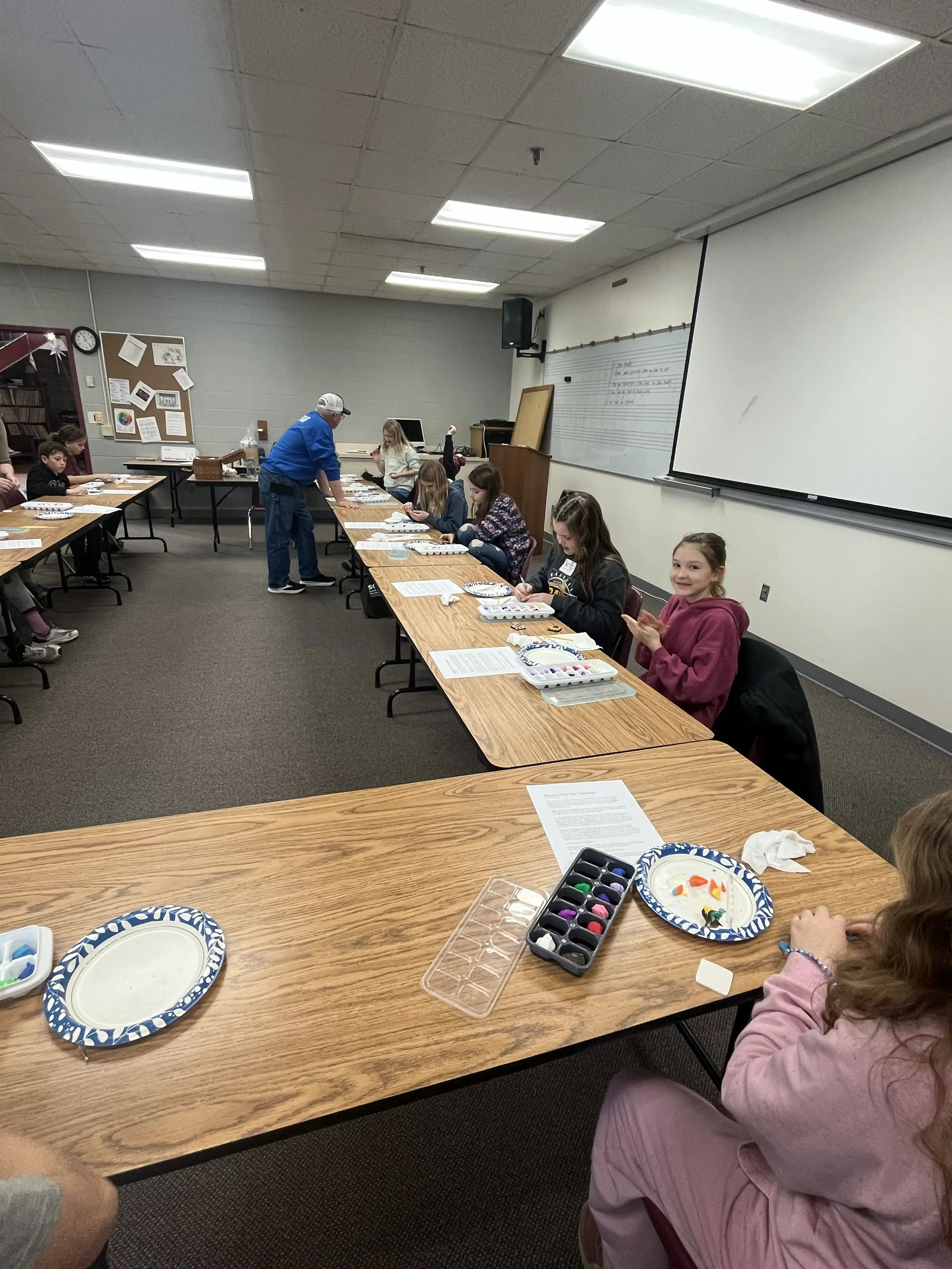 students sitting by tables in a shape of a square with a plate in front of them