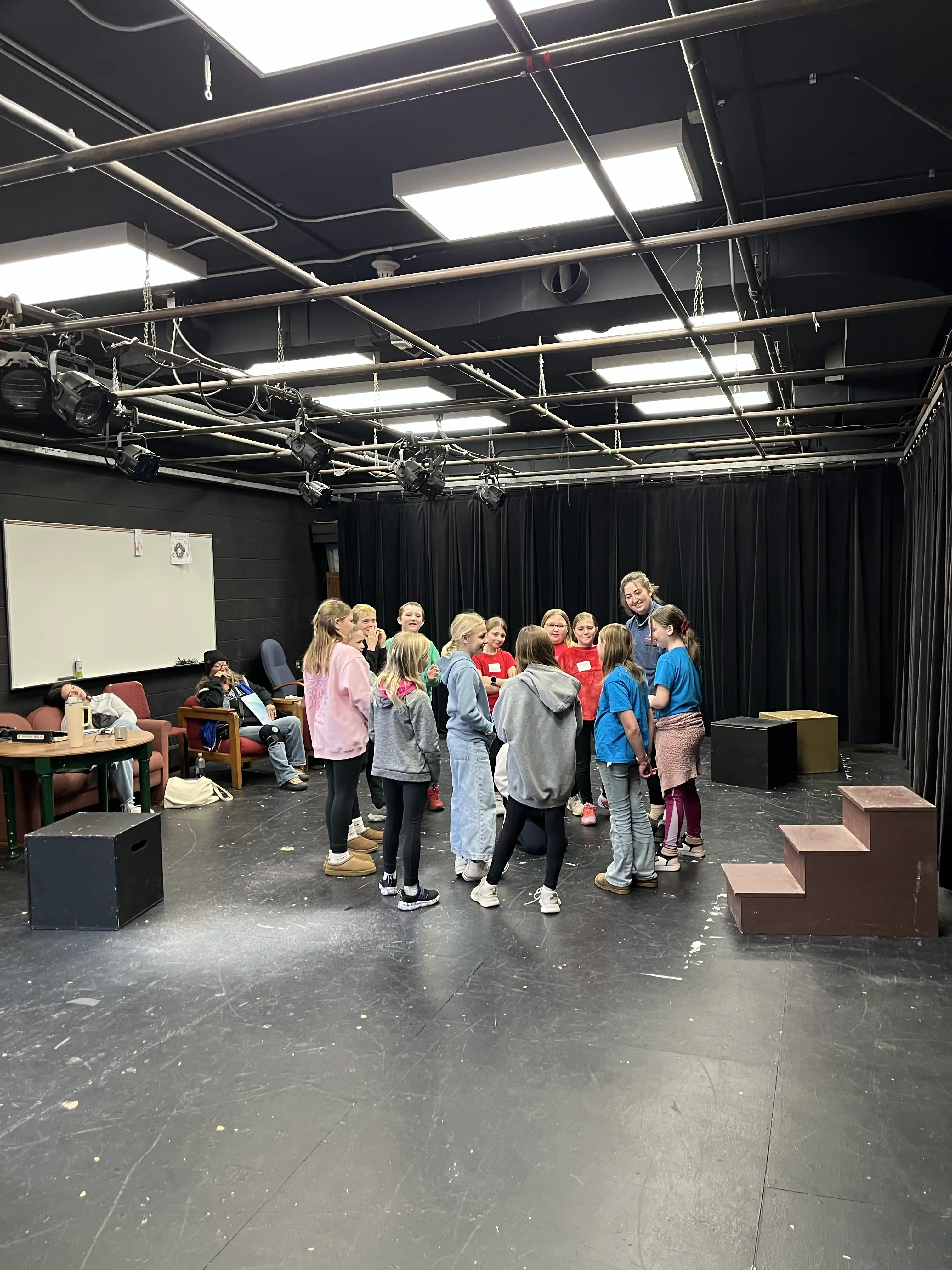 Students standing in a circle with an adult leading a theater game