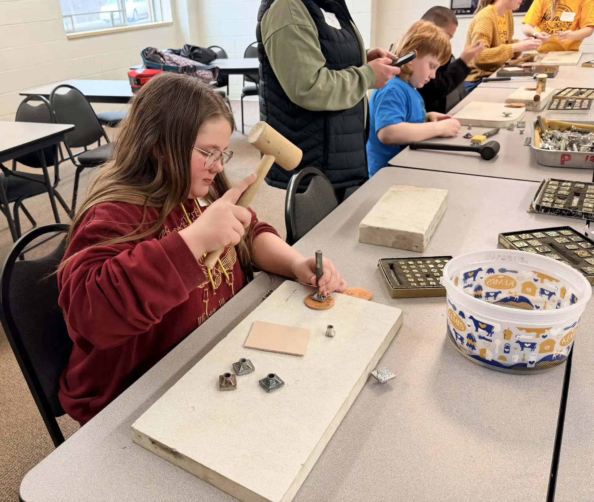 student sitting at a table stamping leather