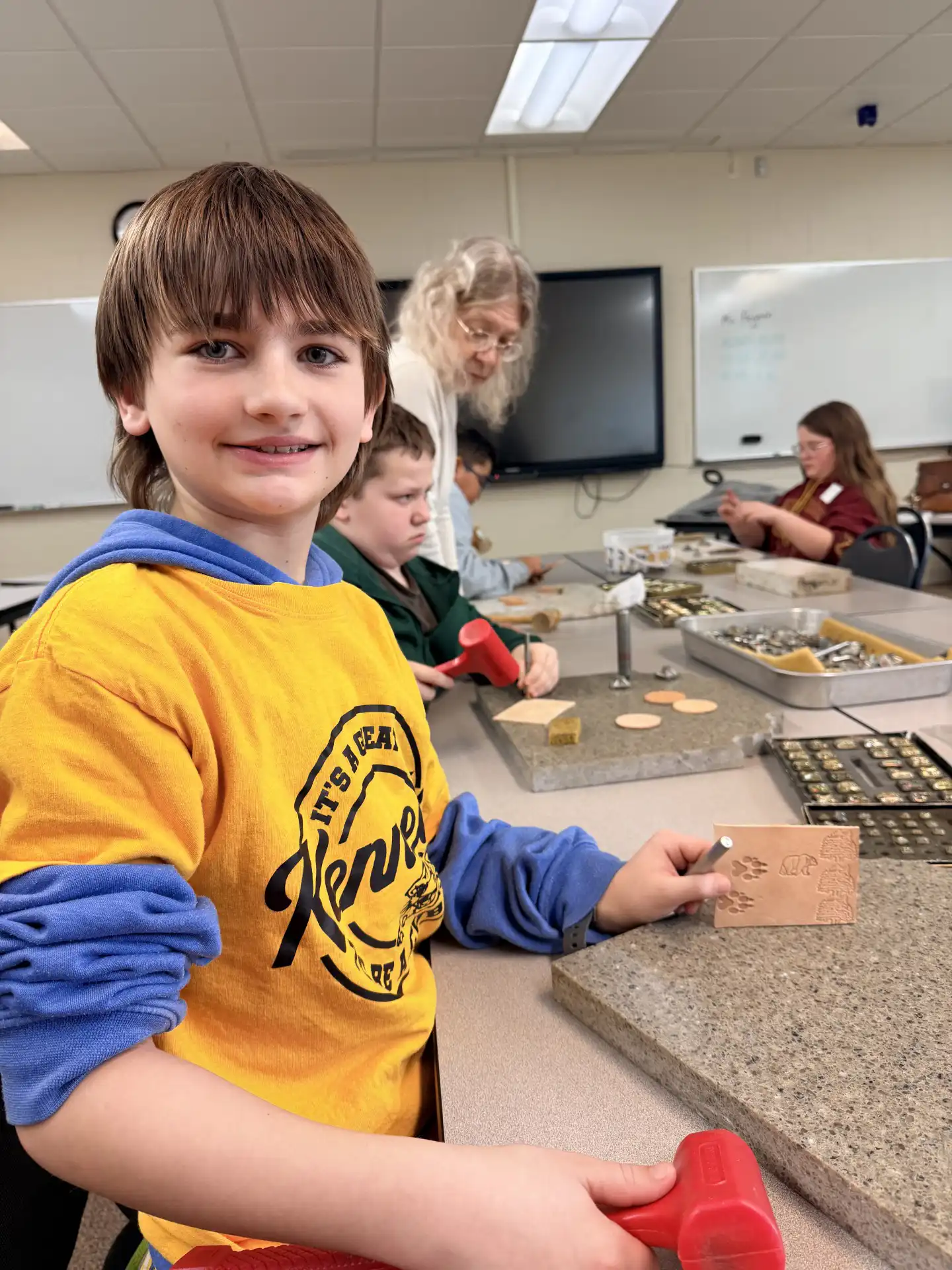 student smiling at the camera and holding up their project