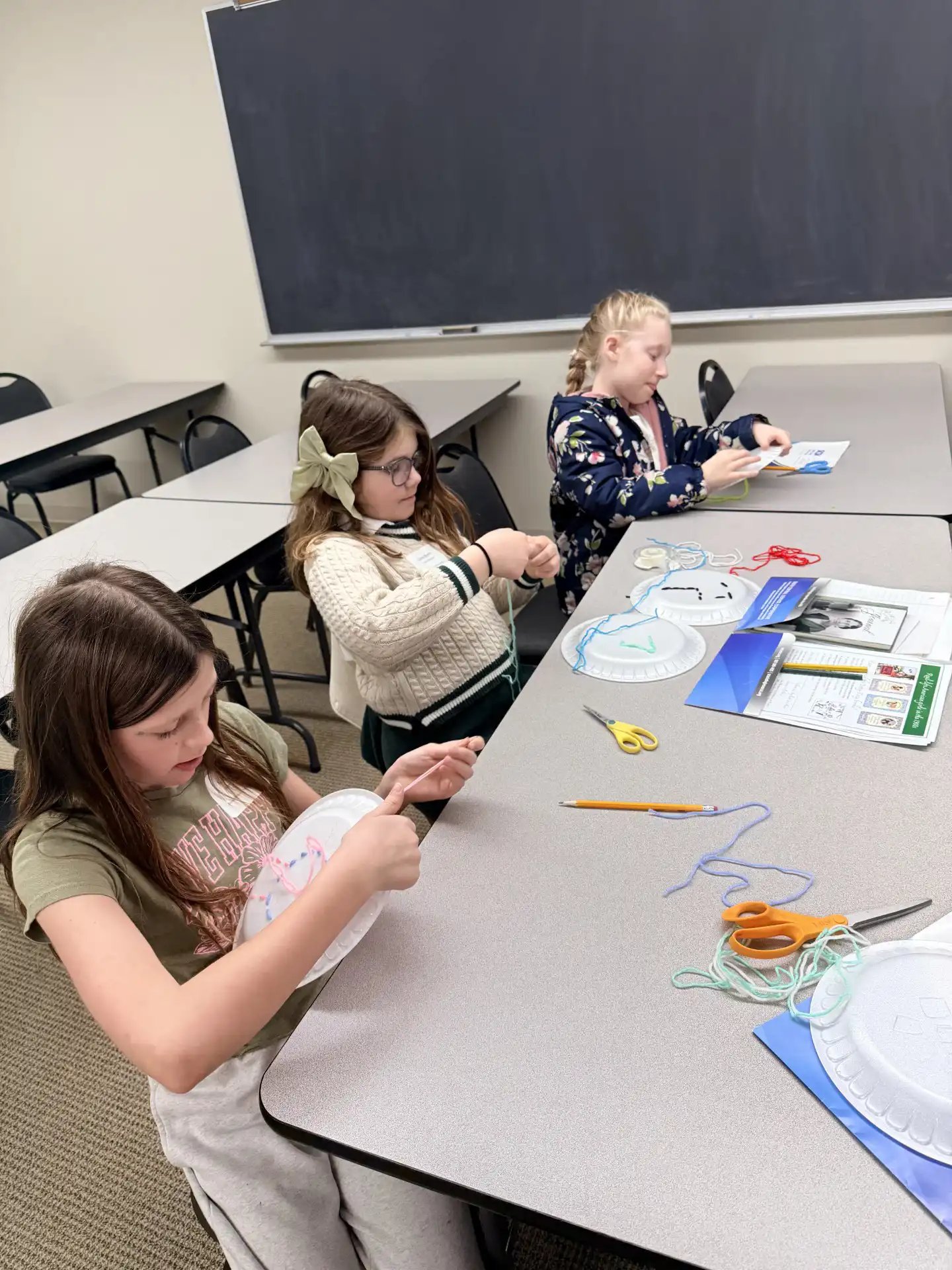 3 students at a table working on an art project