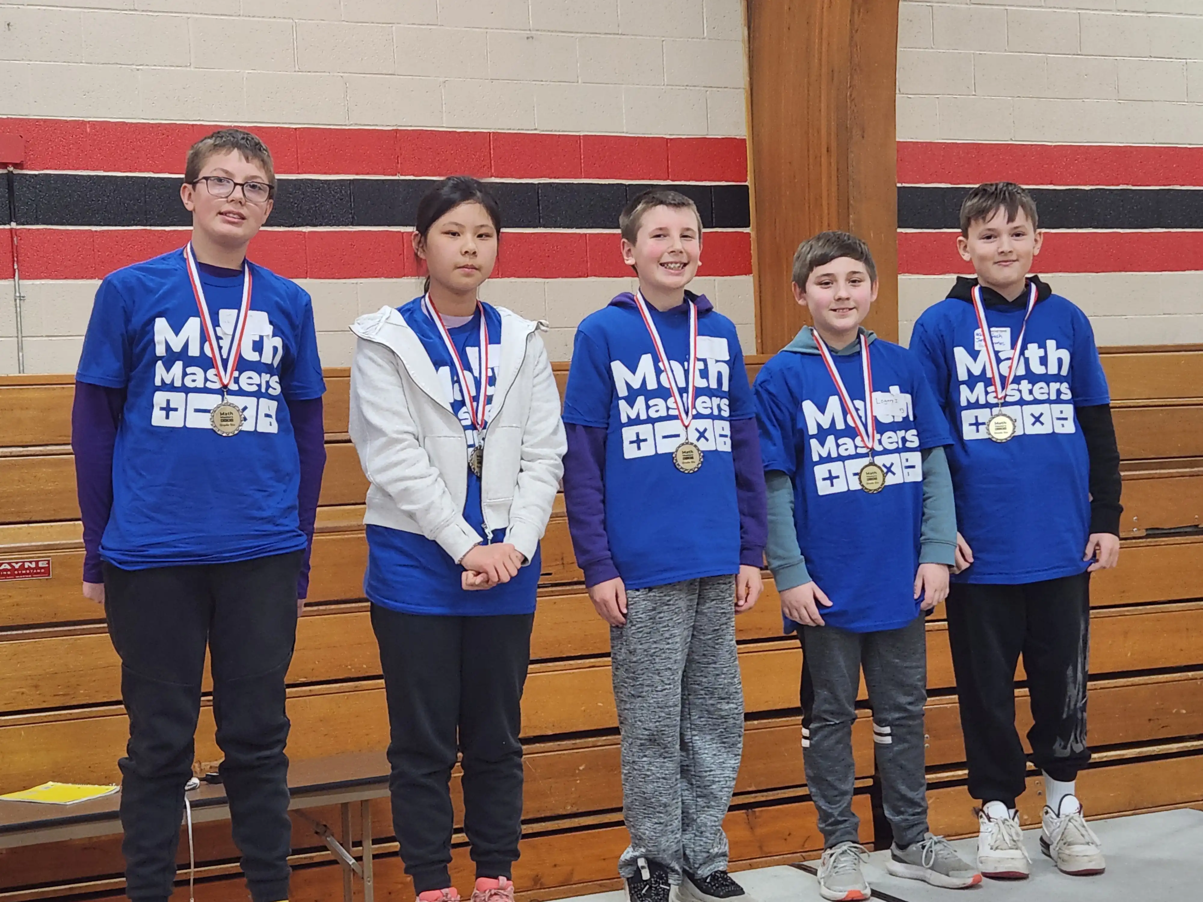 5 students smiling at the camera and wearing their medals they won.