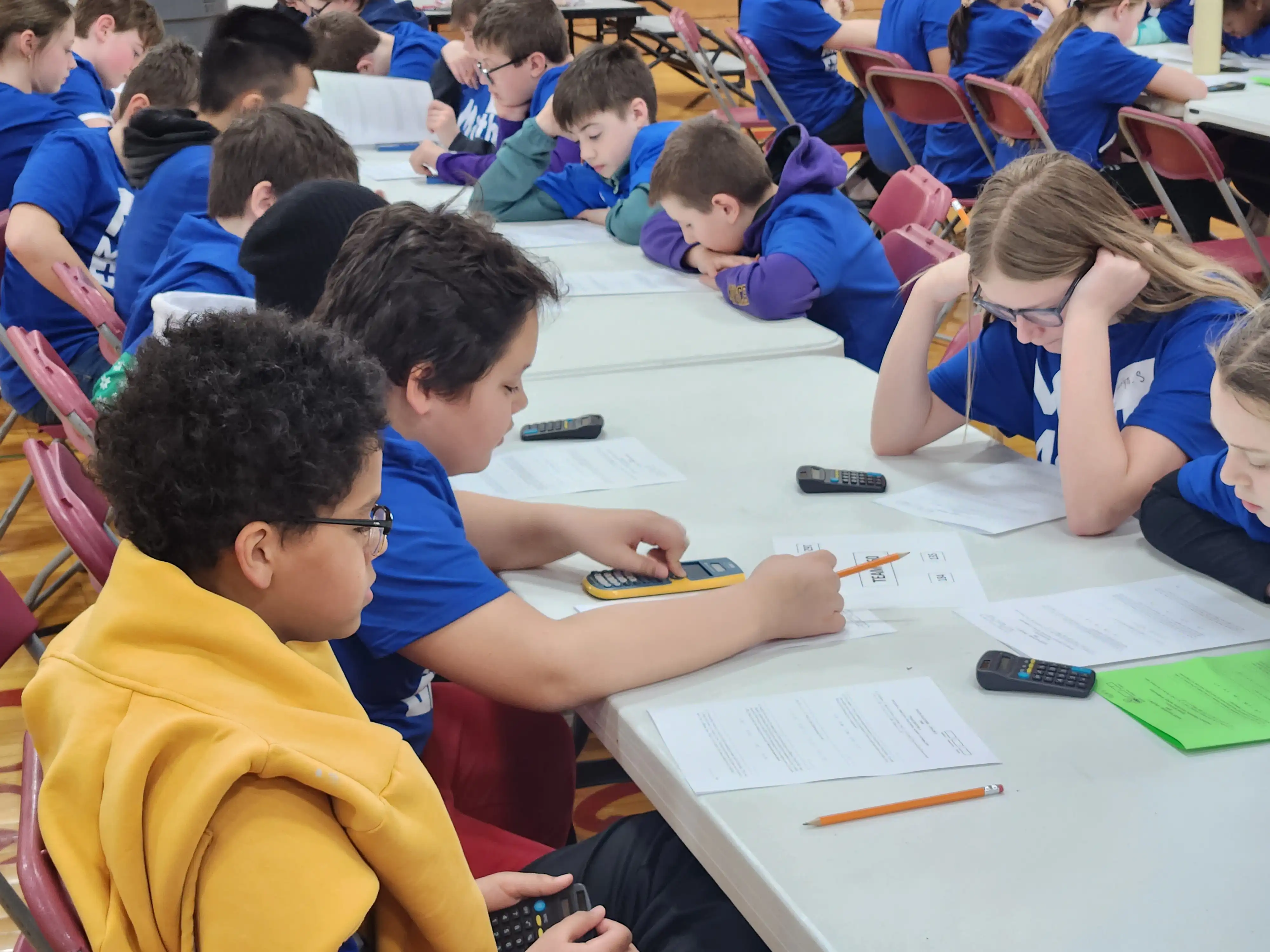 Students sitting by a table working on math problems 