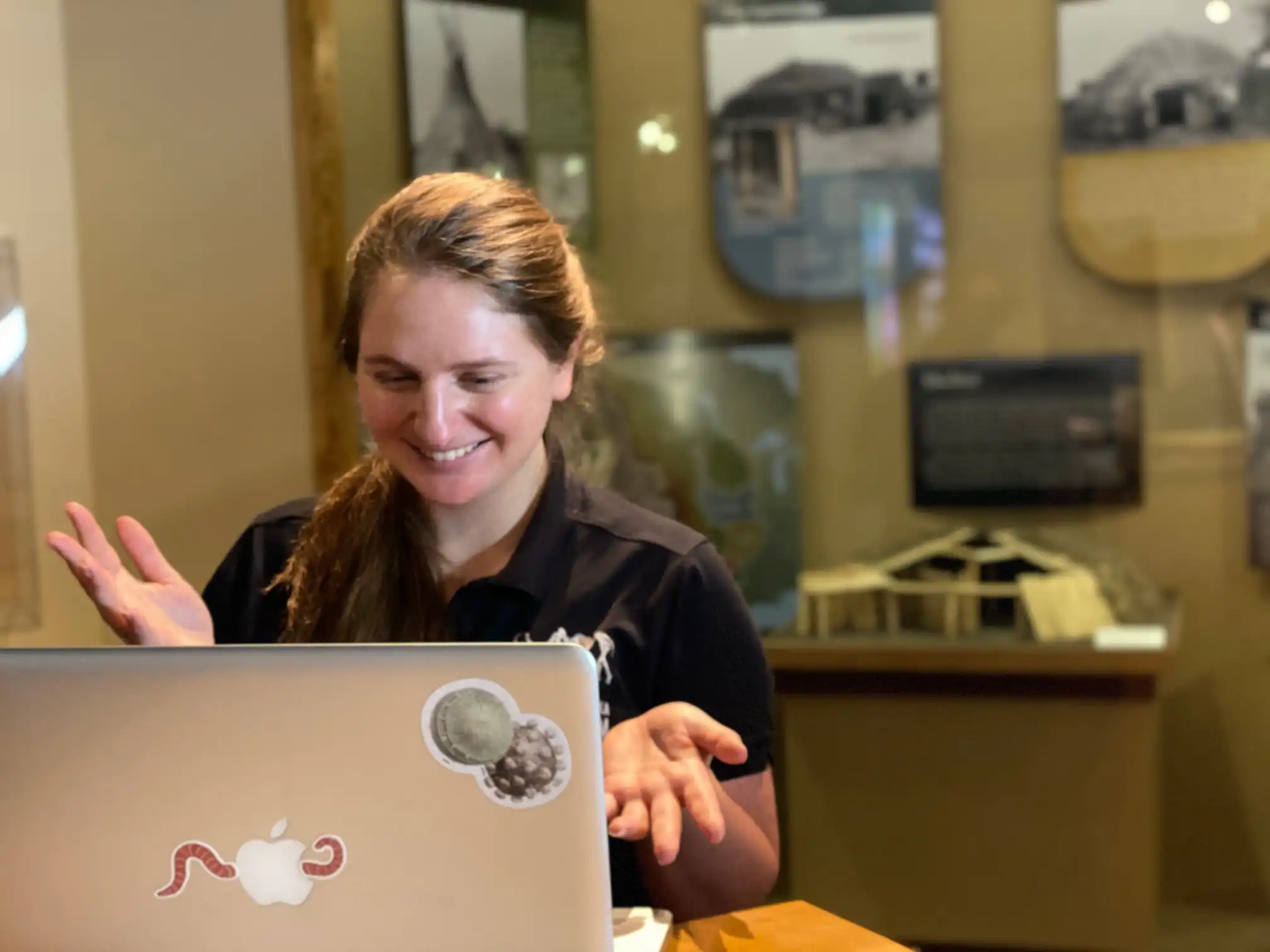 Presenter in a museum gallery standing behind a computer screen that she is using to deliver the program.