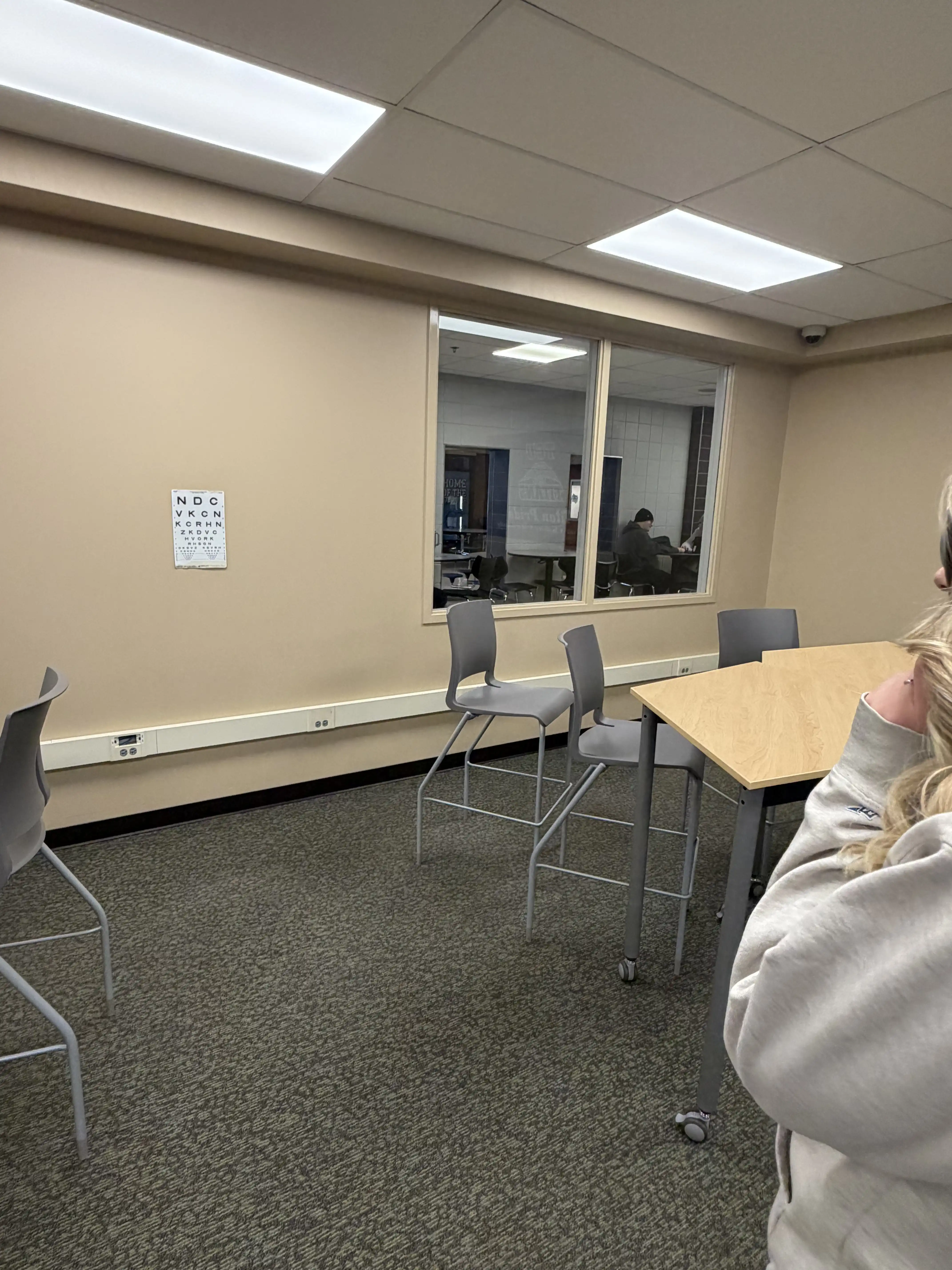 Student on edge of picture looking at eye chart on wall for vision test