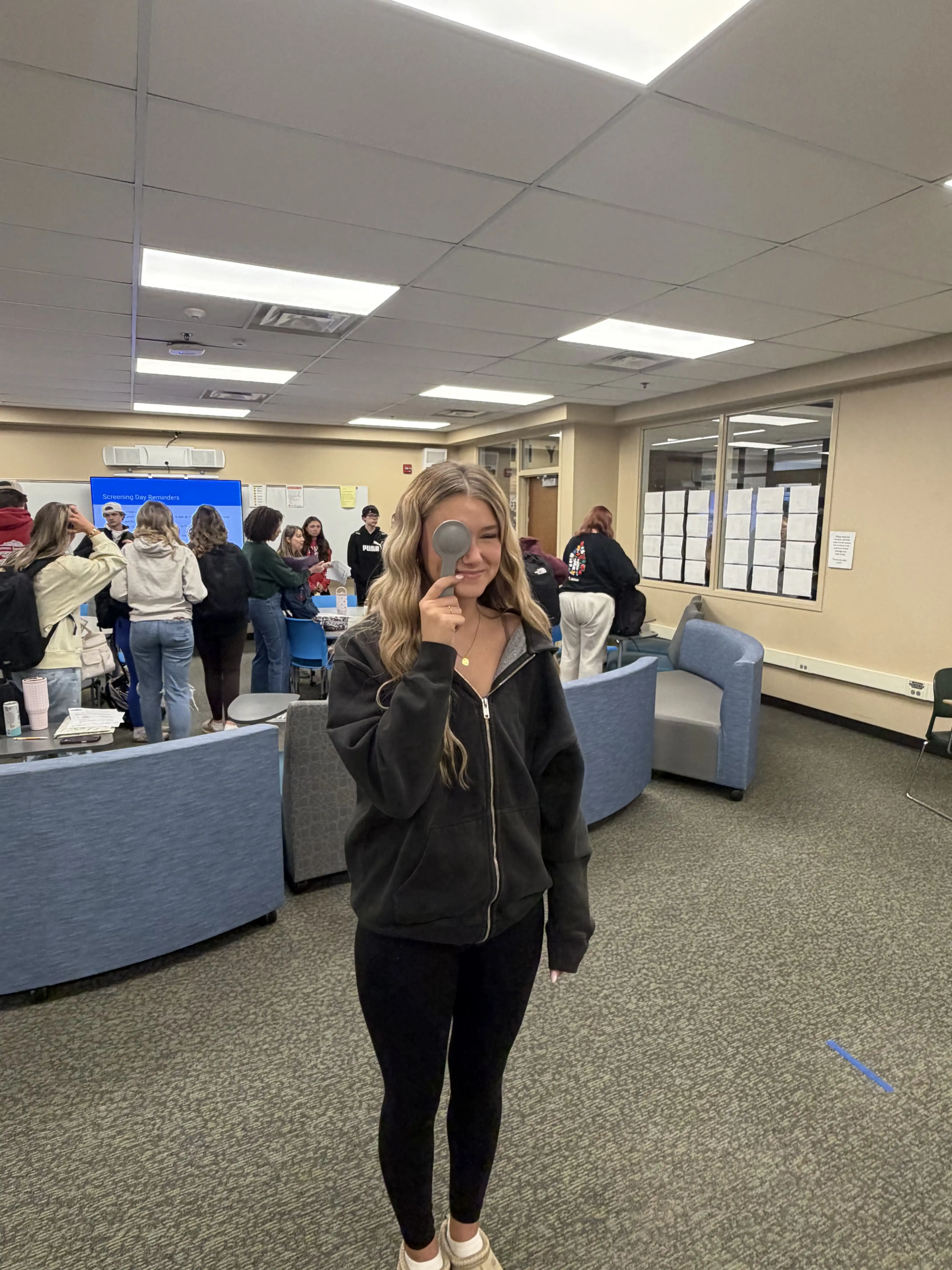 Student standing covering one eye and getting ready to do an eye exam.