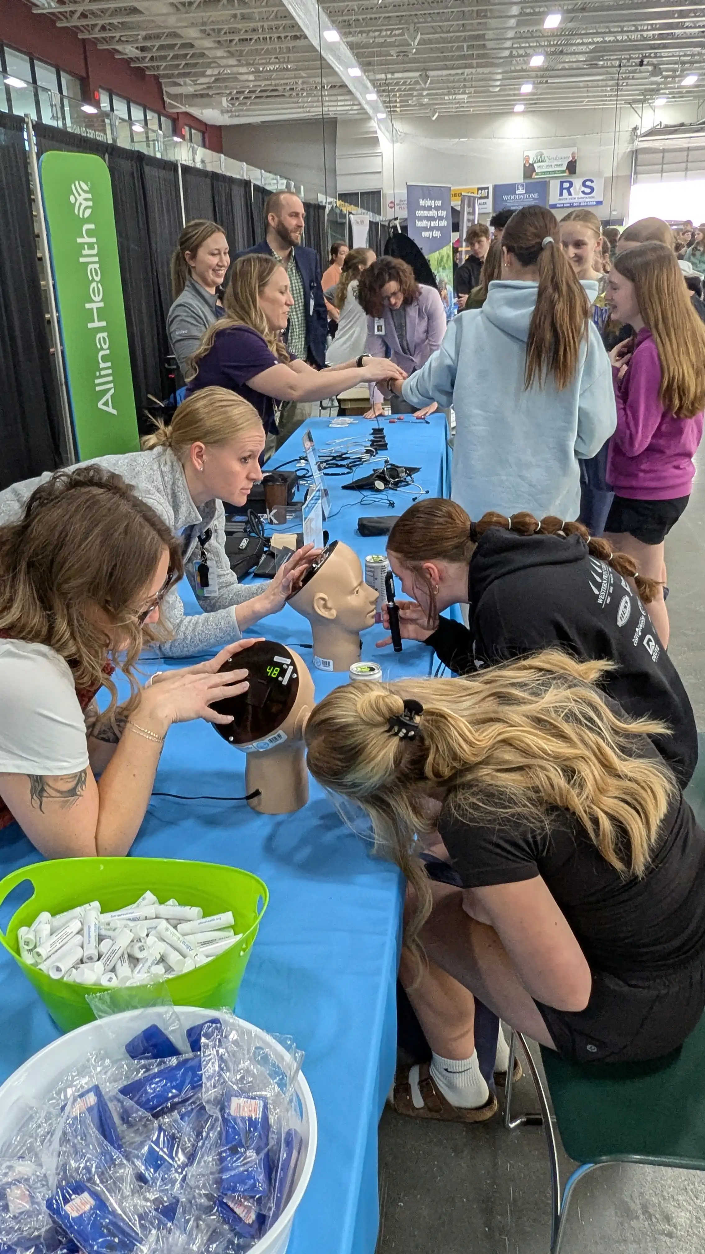 Students standing by a table doing an eye exam on a medical doll.