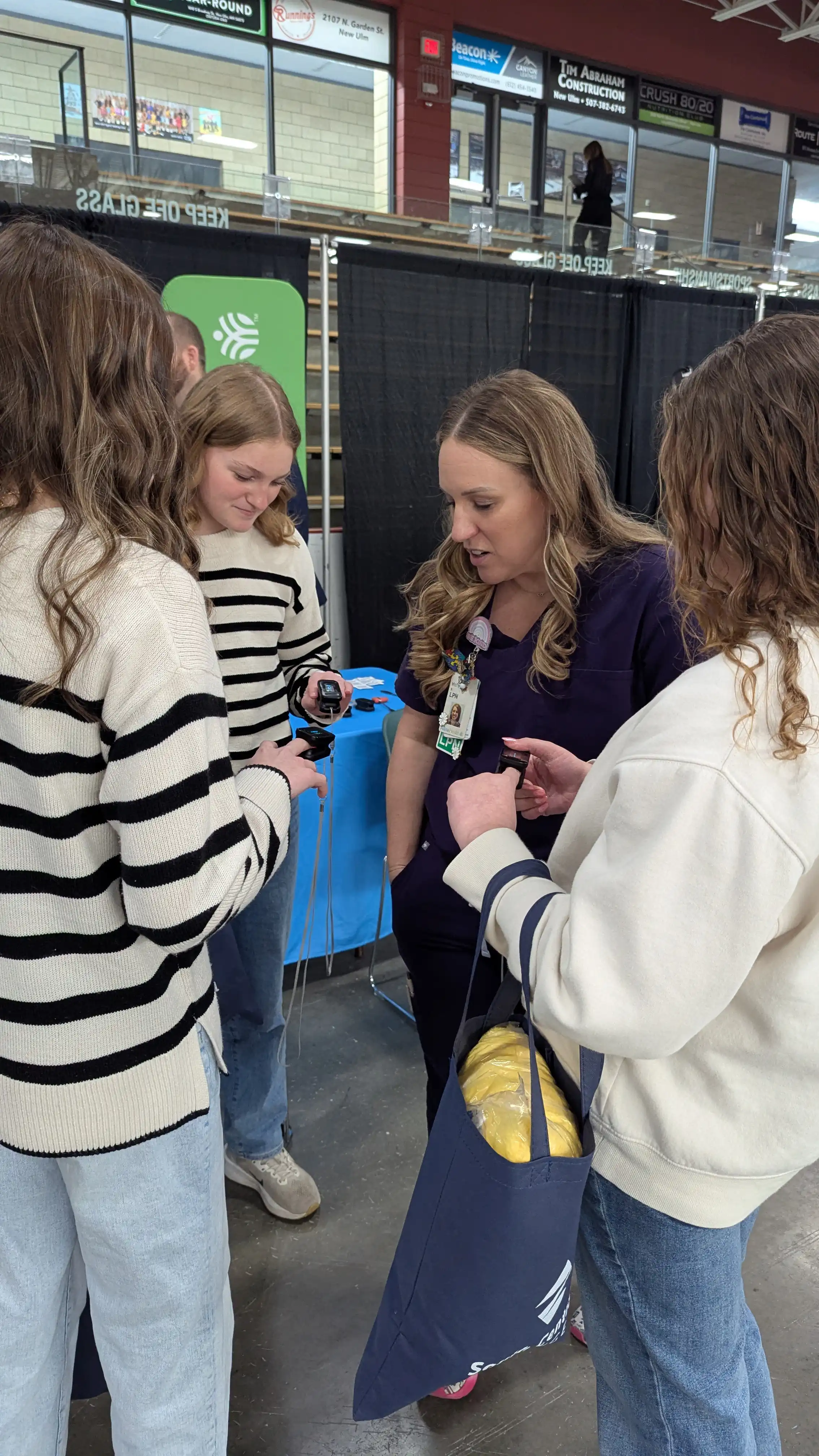 A group of students standing in the circle talking while taking pulse on their finger
