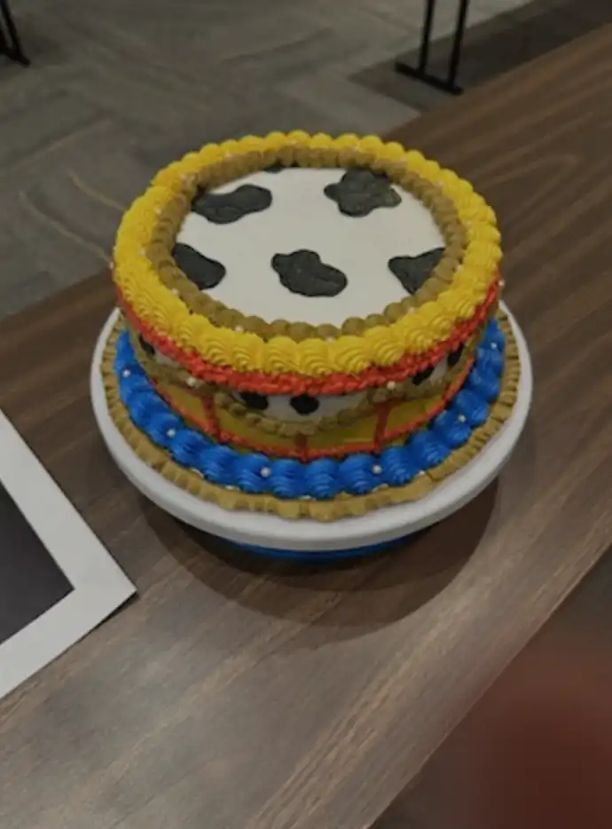 Cake decorated with a cow pattern, belt and blue on it.