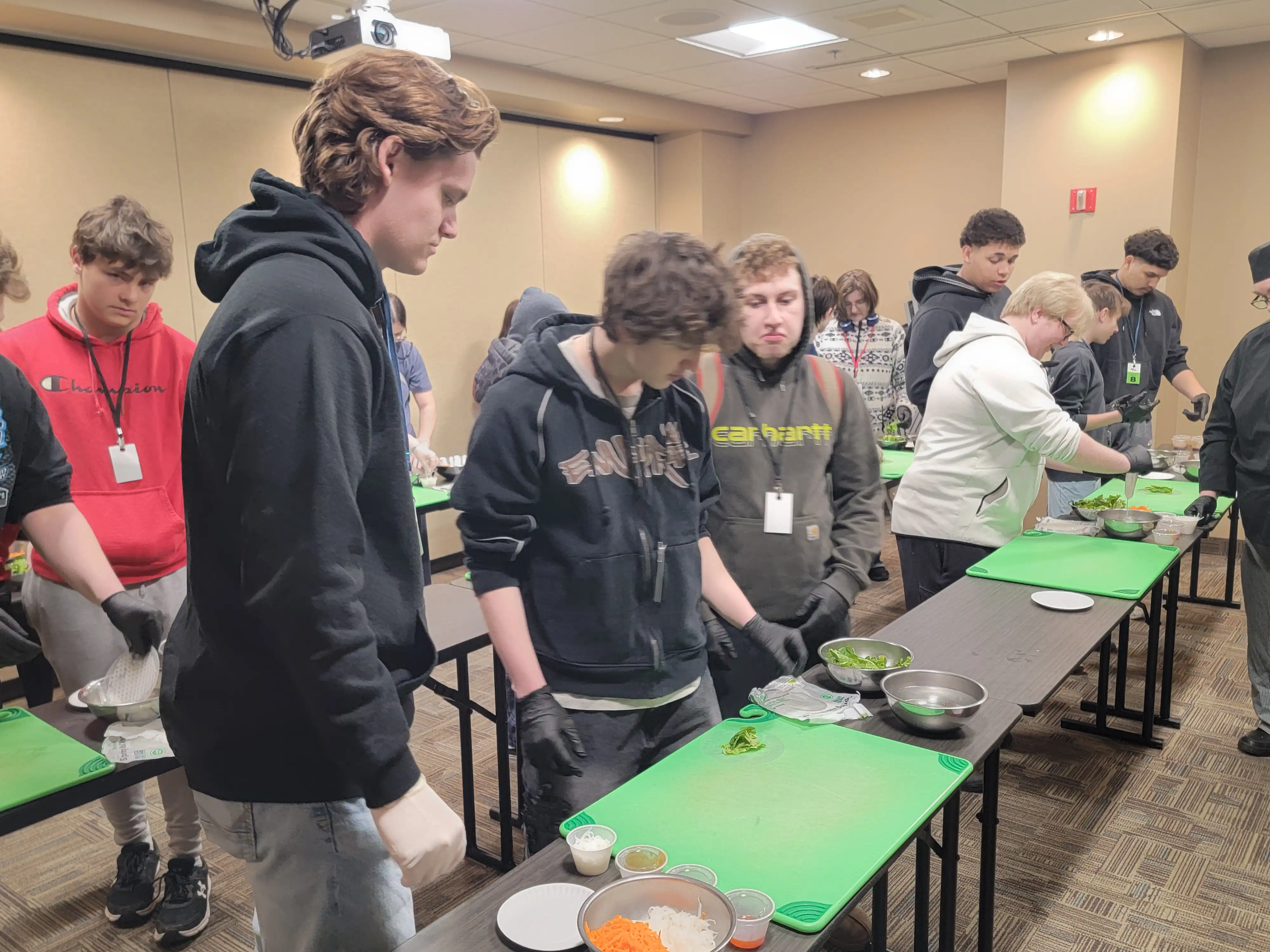 Students standing by tables with cutting boards on them getting ready to cut fruit