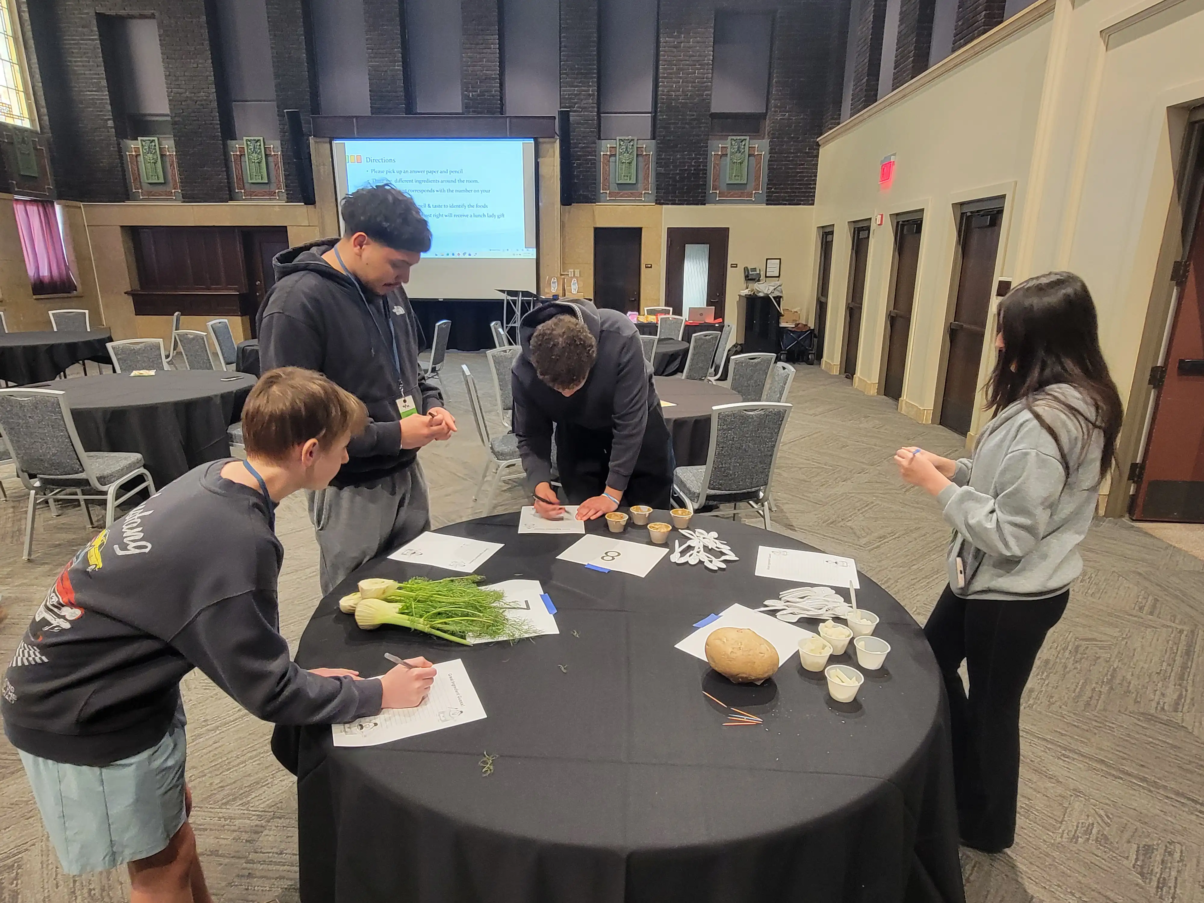 Students standing around a table working on paper work.