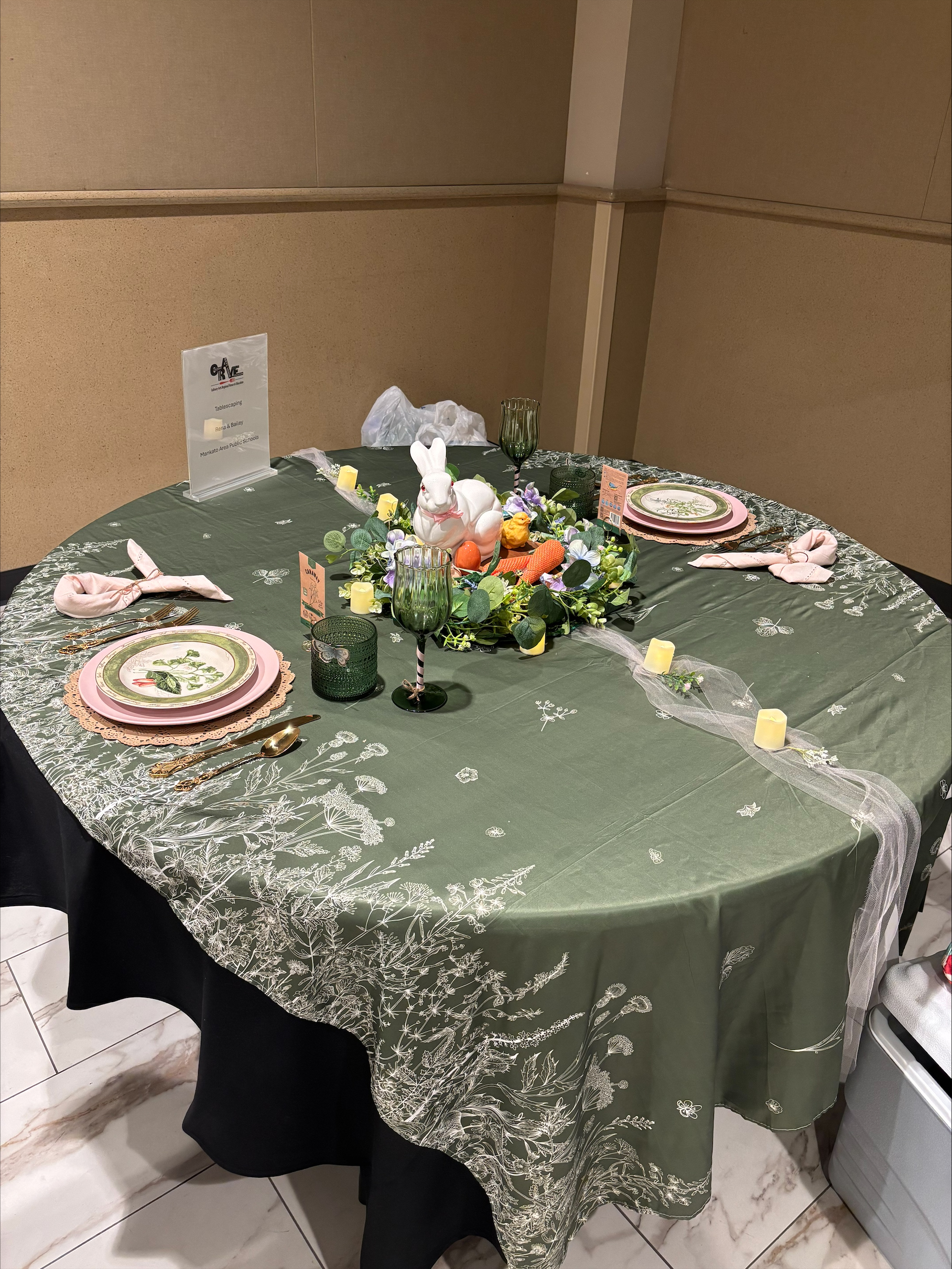 Table decorated with green table cloth and pink dishes