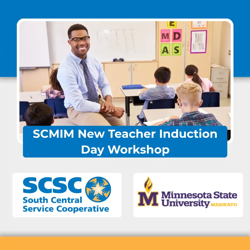 Teacher smiling and sitting on his desk with students working at their desks in the background