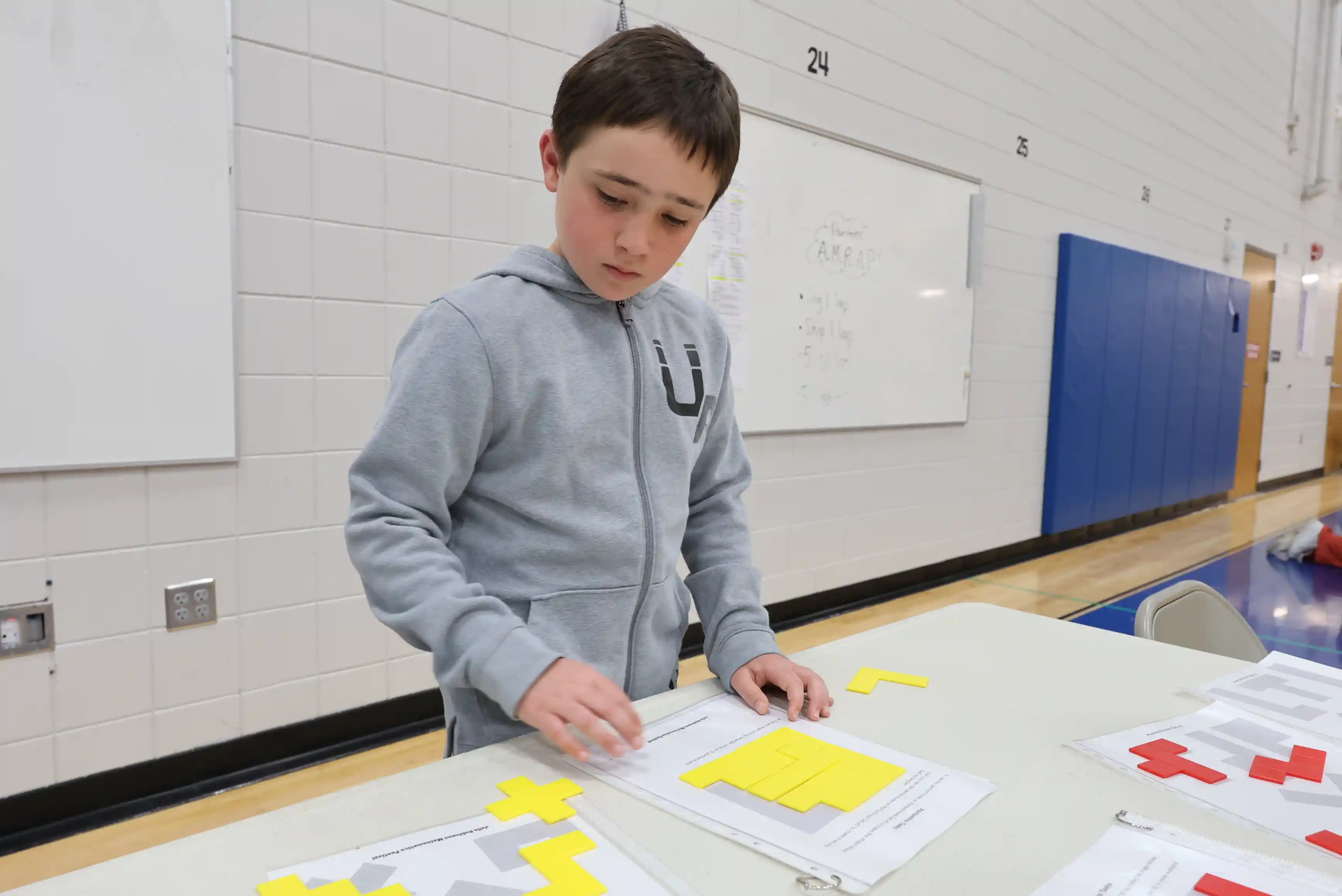 student moving around shapes to make bigger shapes at a table